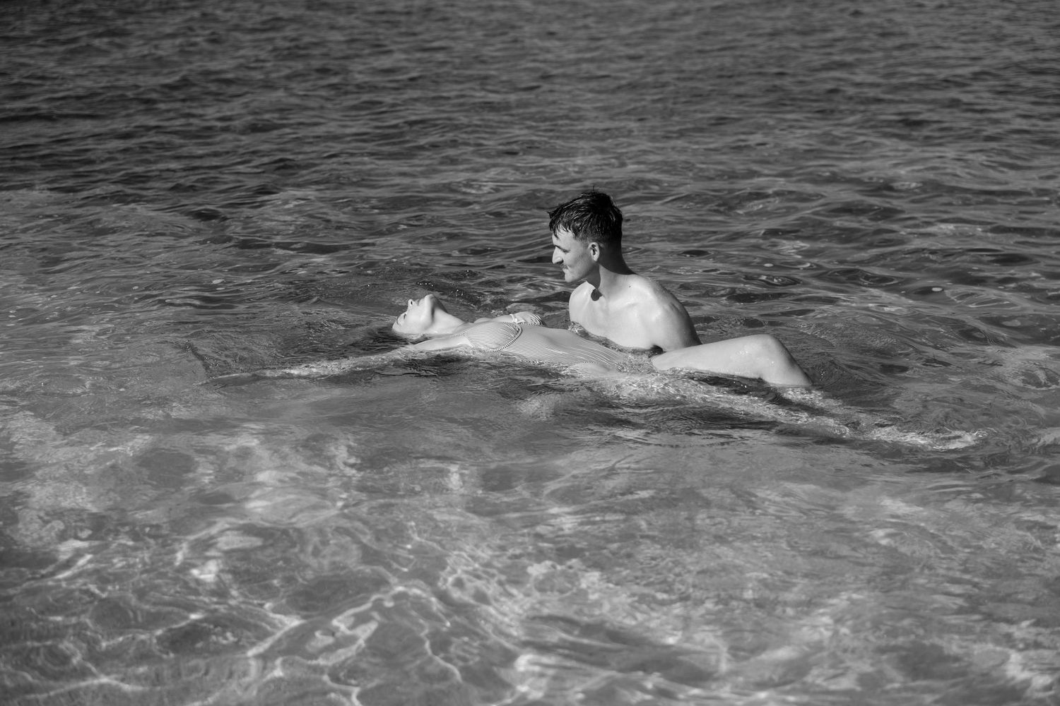 People swimming and floating in dark ocean waters at dusk.
