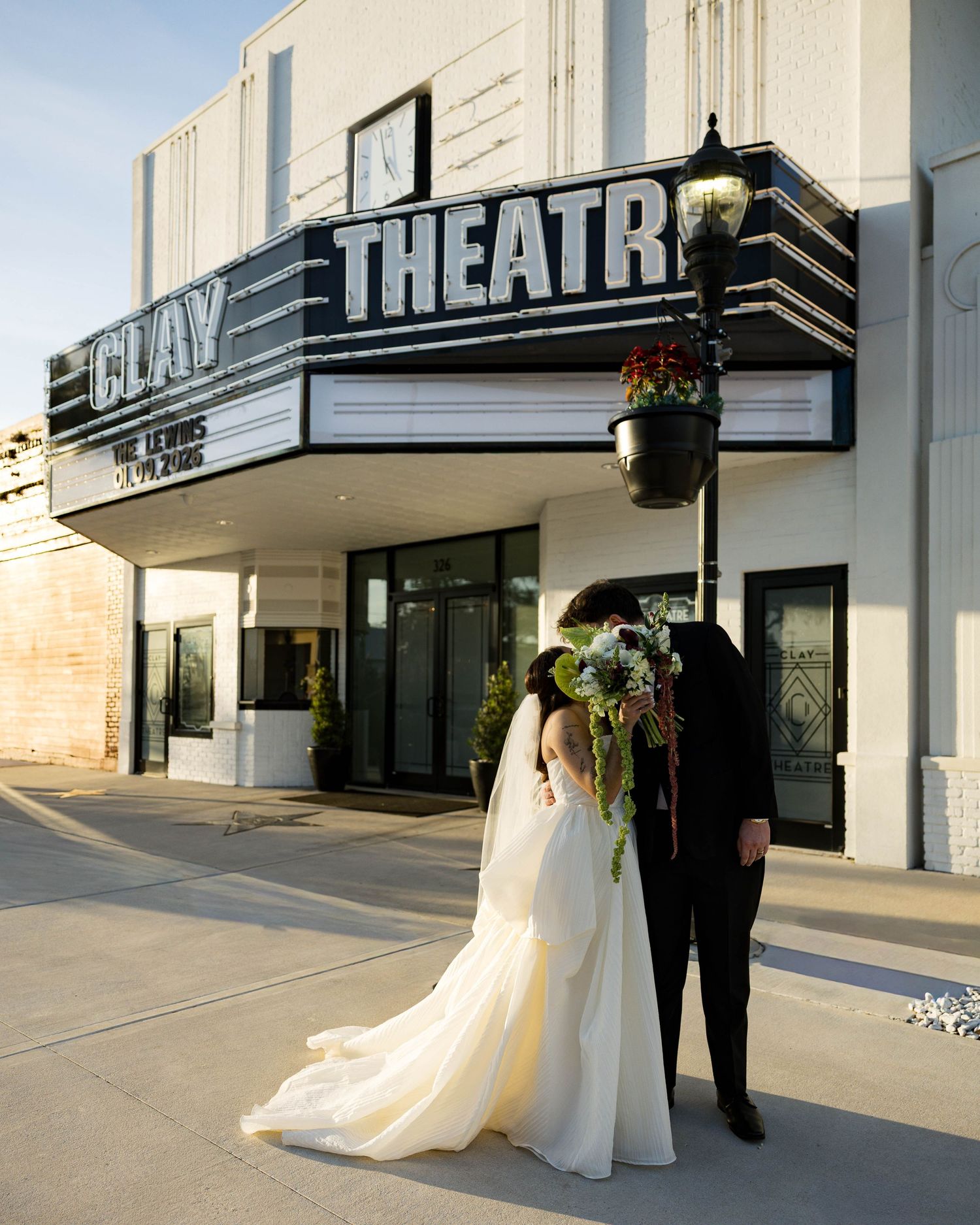 Wedding couple standing beneath the classic Clay Theatre marquee at sunset.