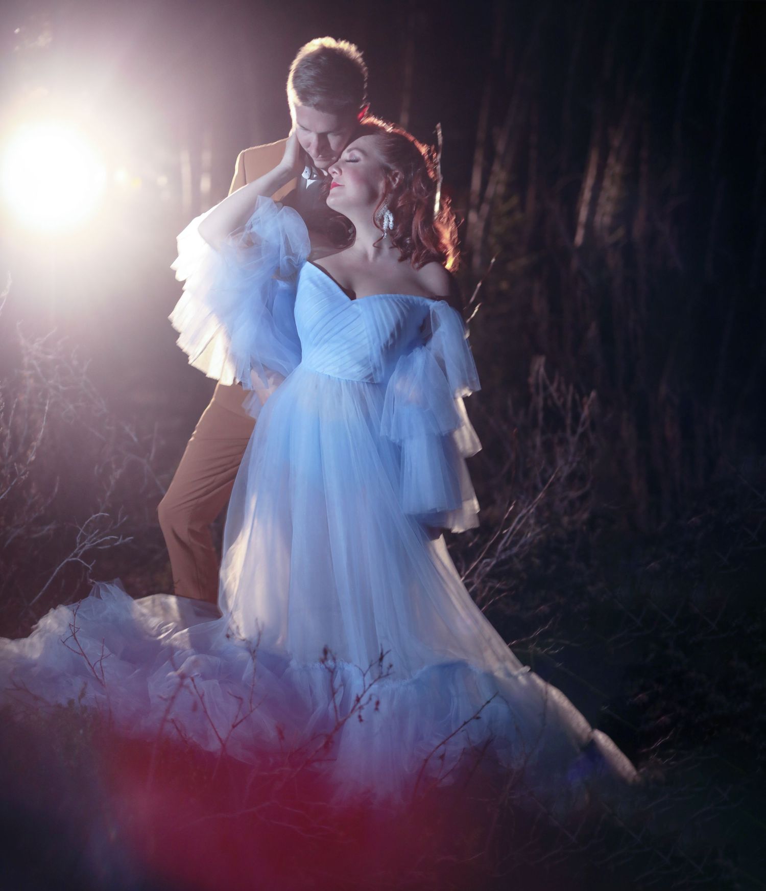A romantic couple in a magical nighttime scene with ethereal lighting and flowing light blue wedding dress in Kananaskis Country Canada