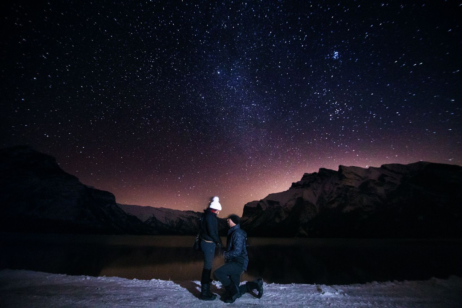 Man proposing to his girlfriend at night under the milky way starry sky in Banff national park canada.