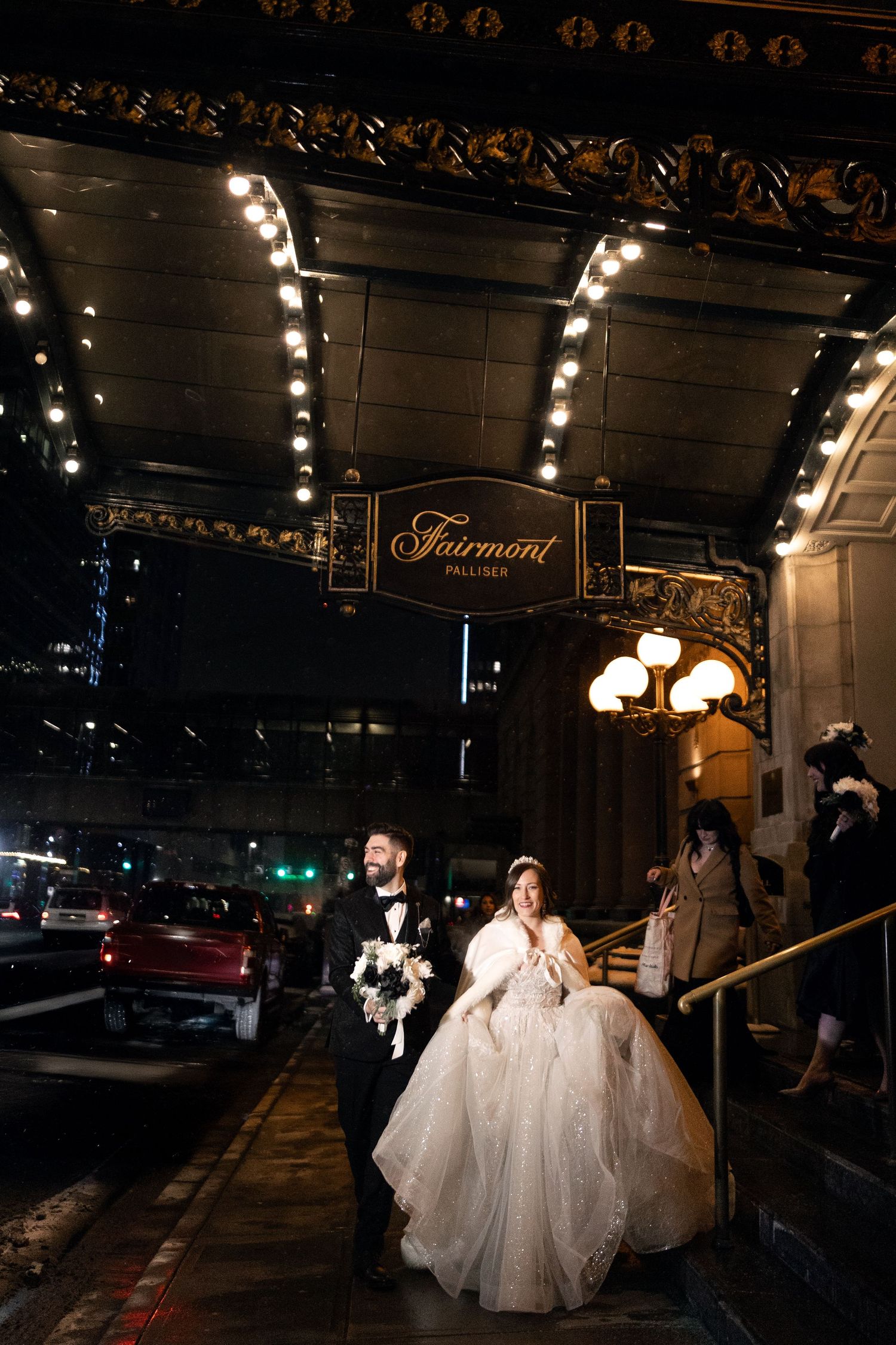 A glamorous night scene outside the Fairmont Palliser downtown Calgary showcasing a bride and groom walk out on their snowy wedding night