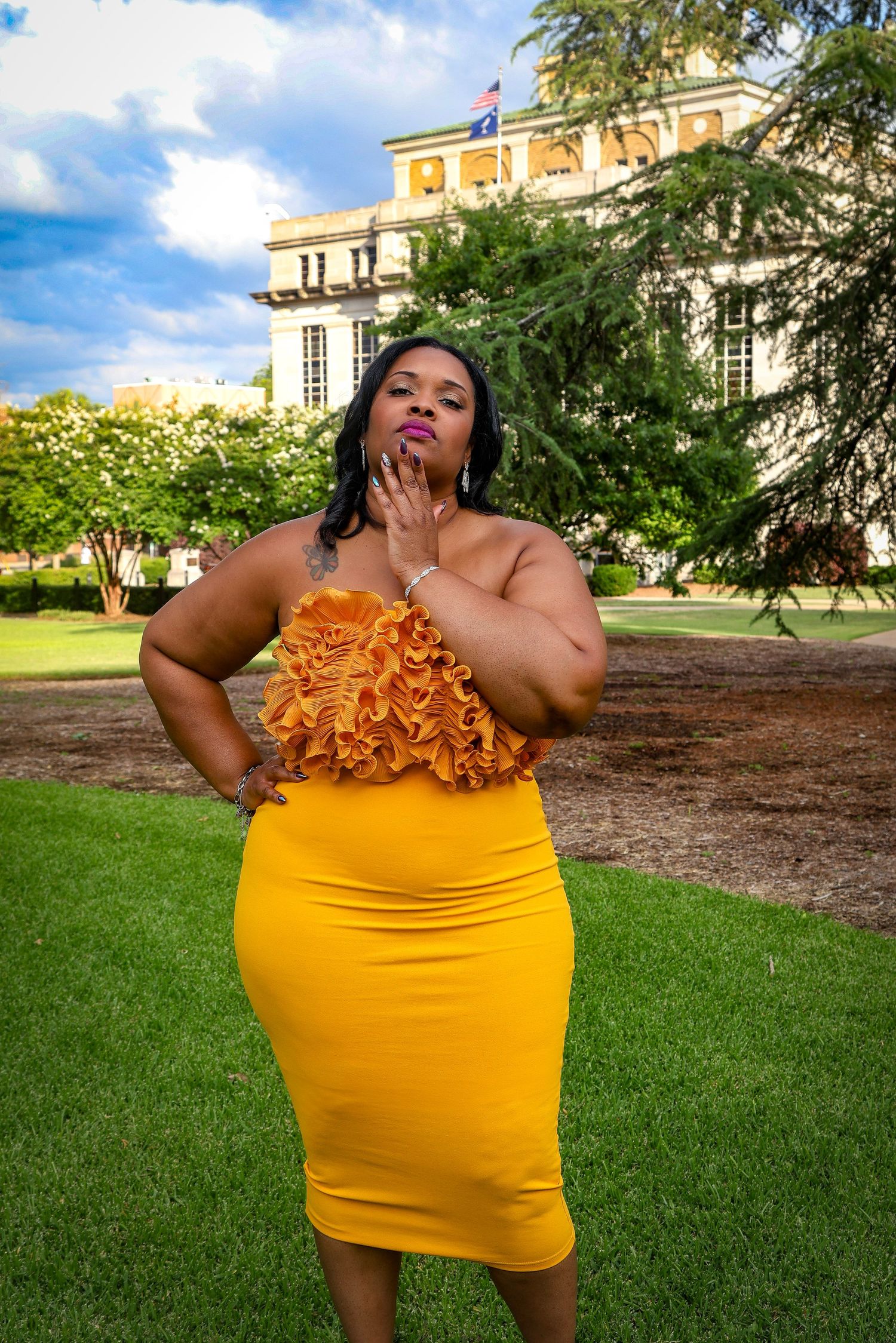 Outdoor fashion photography session showcasing yellow ruffle dress against classic architecture.