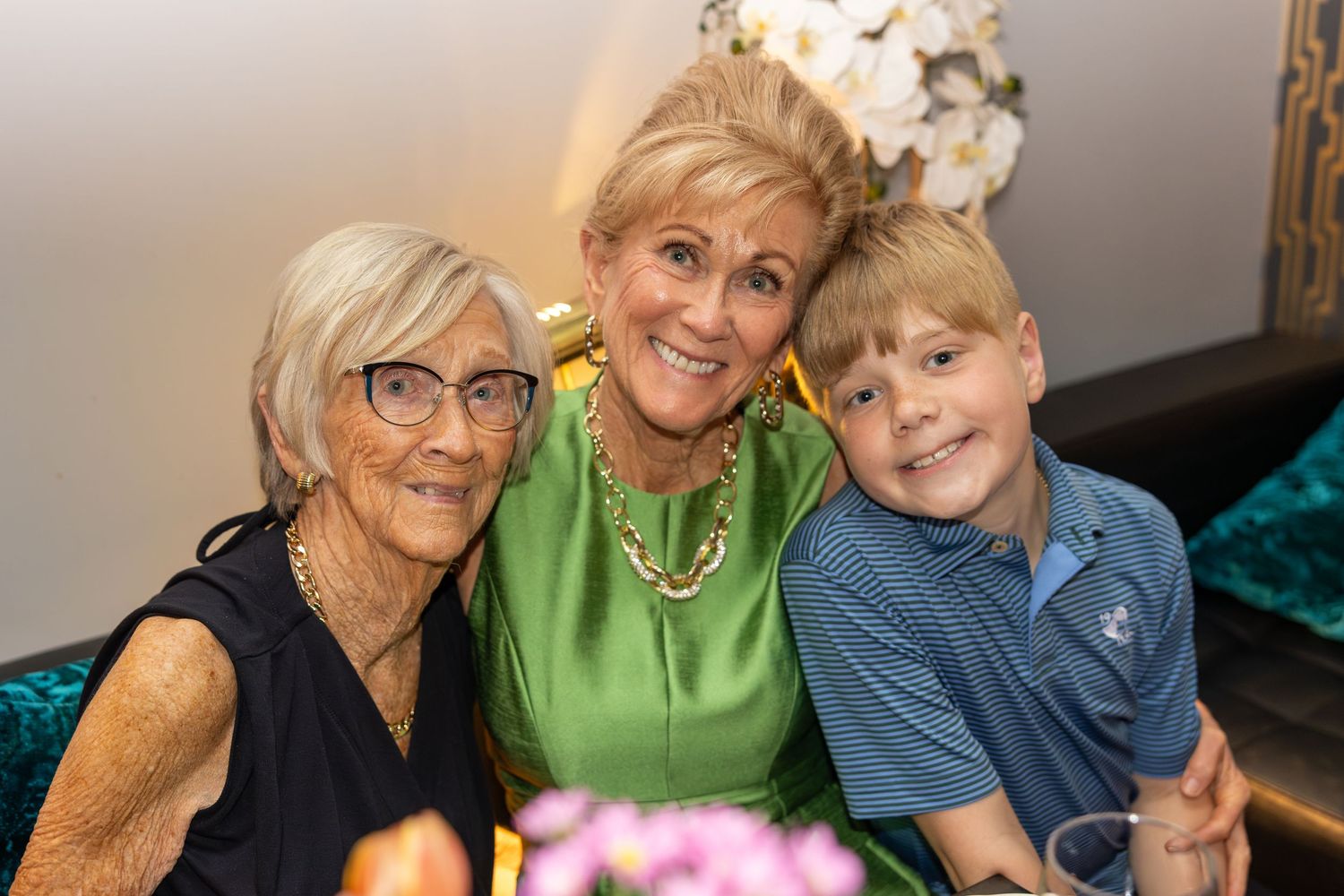 Three generations of women and a young boy smiling together at a family celebration event.