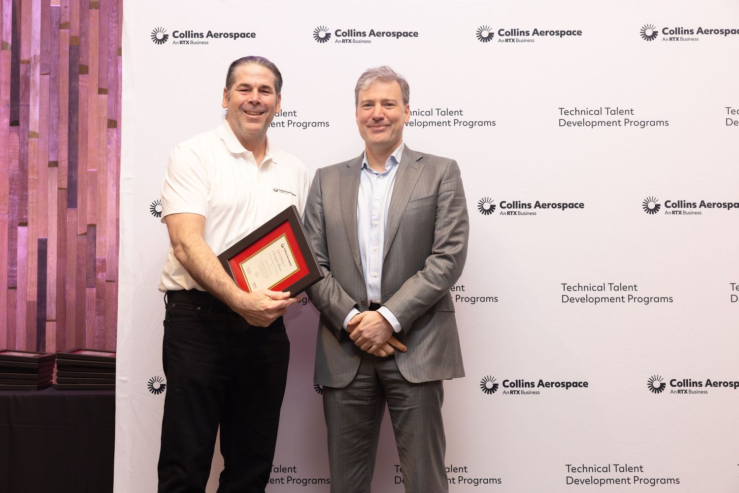 Two men proudly display a framed award at Collins Aerospace Technical Talent Development Programs event.