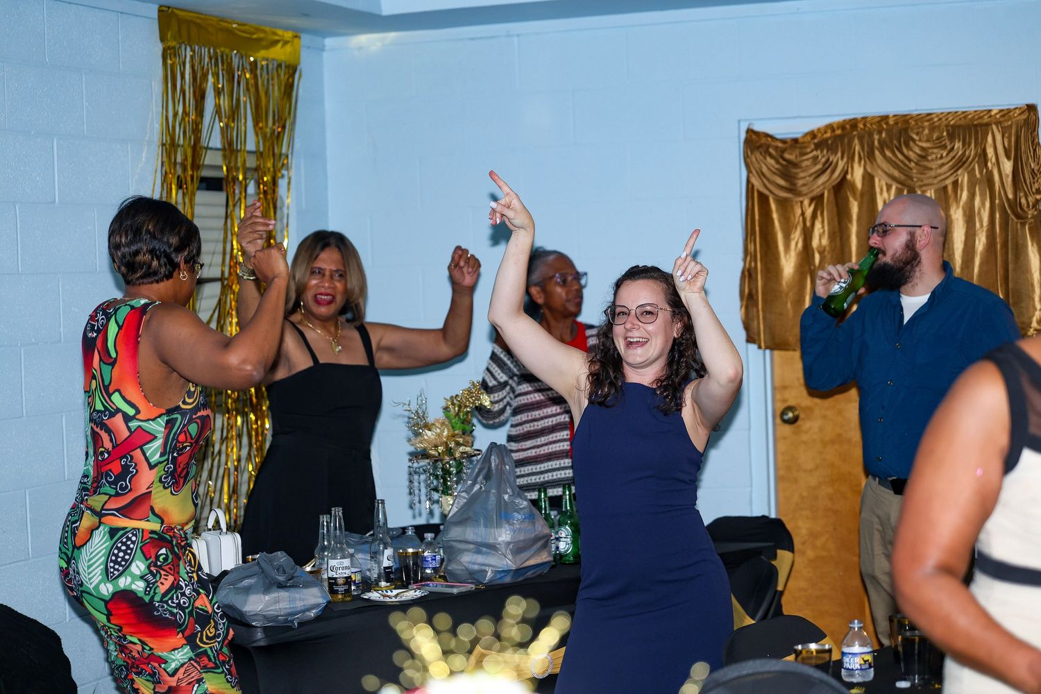 People dancing and celebrating at a lively indoor party with gold decorations.