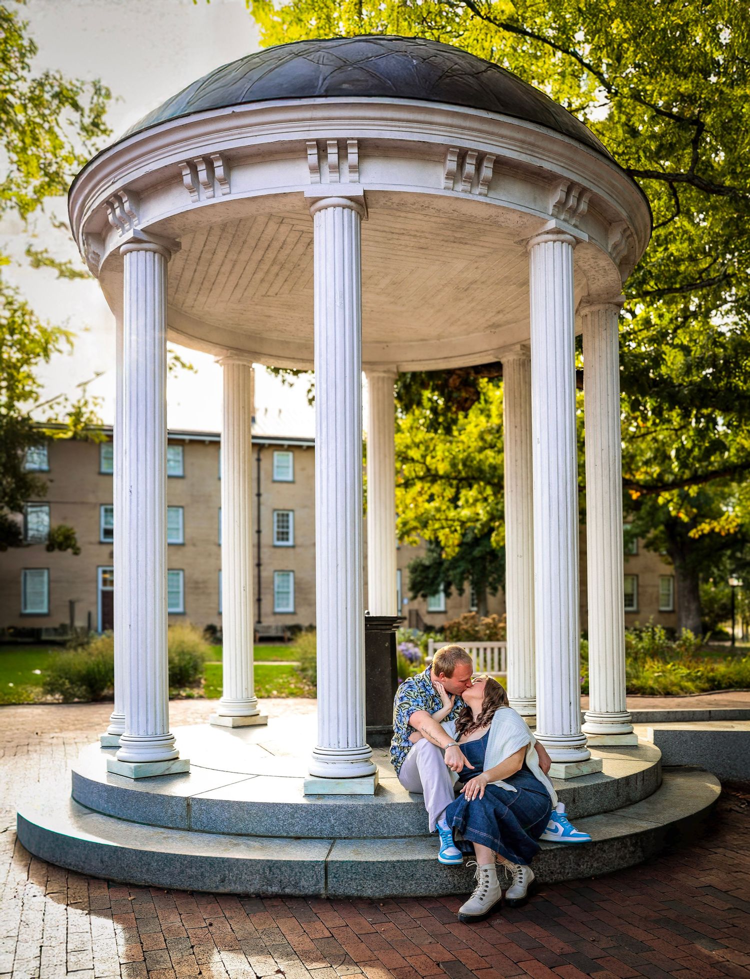 White columned gazebo on college campus with people sitting inside.