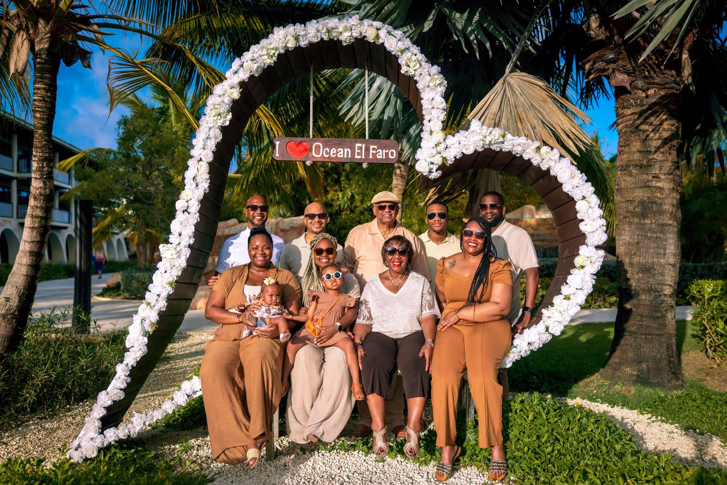 Tropical beach wedding ceremony setup with white floral arch and palm trees along the shoreline.