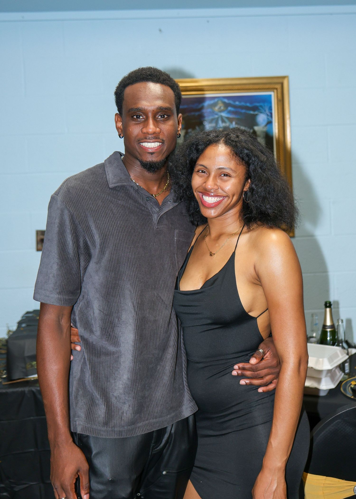 Couples in casual and formal attire pose together at an indoor gathering.