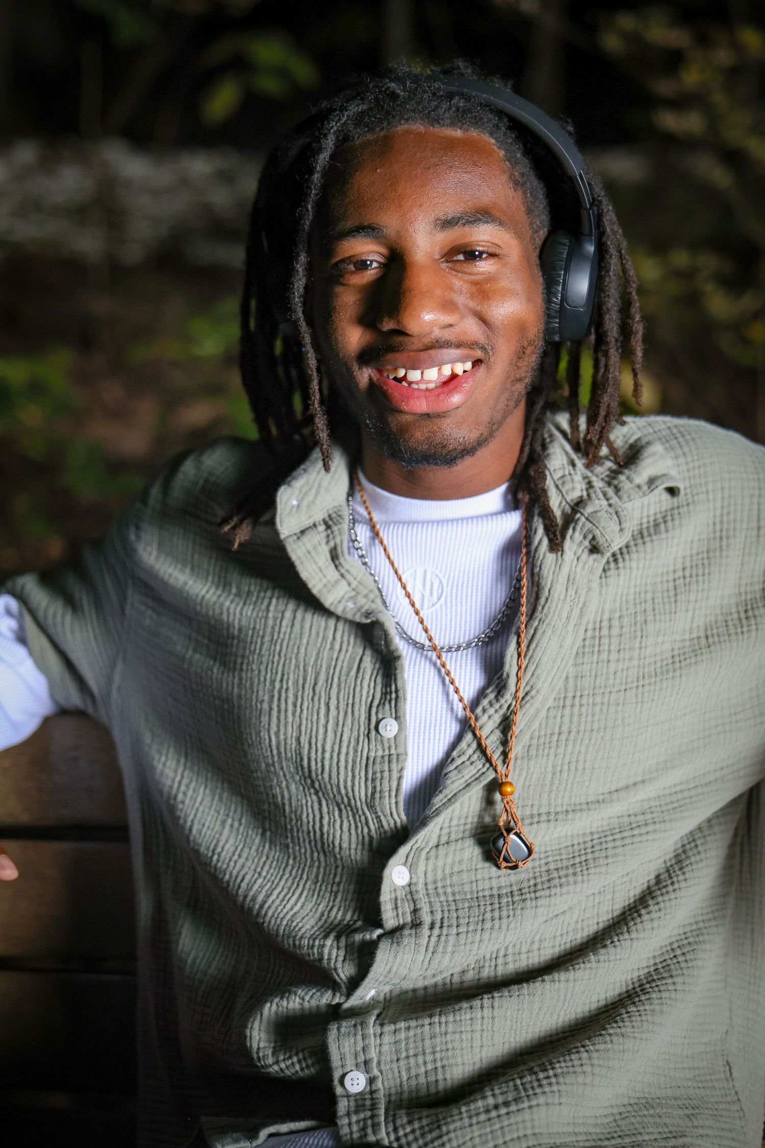 Person in gray sweater and headphones enjoying outdoor portrait session.