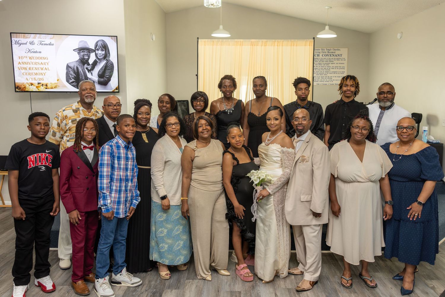 Large family group poses together indoors at a wedding celebration, dressed in elegant formal attire.