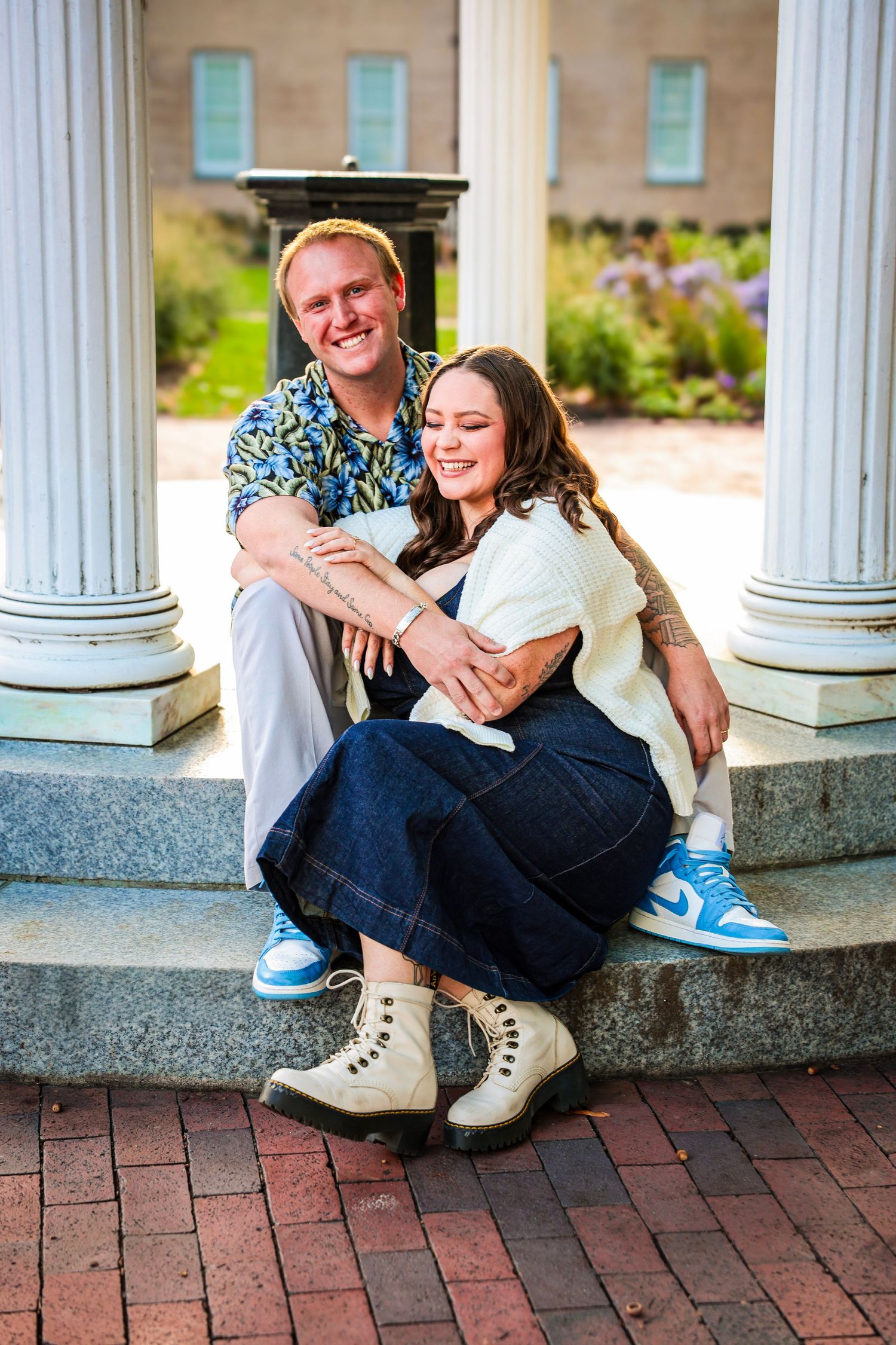 Casual engagement photos taken under a white columned gazebo on campus grounds.