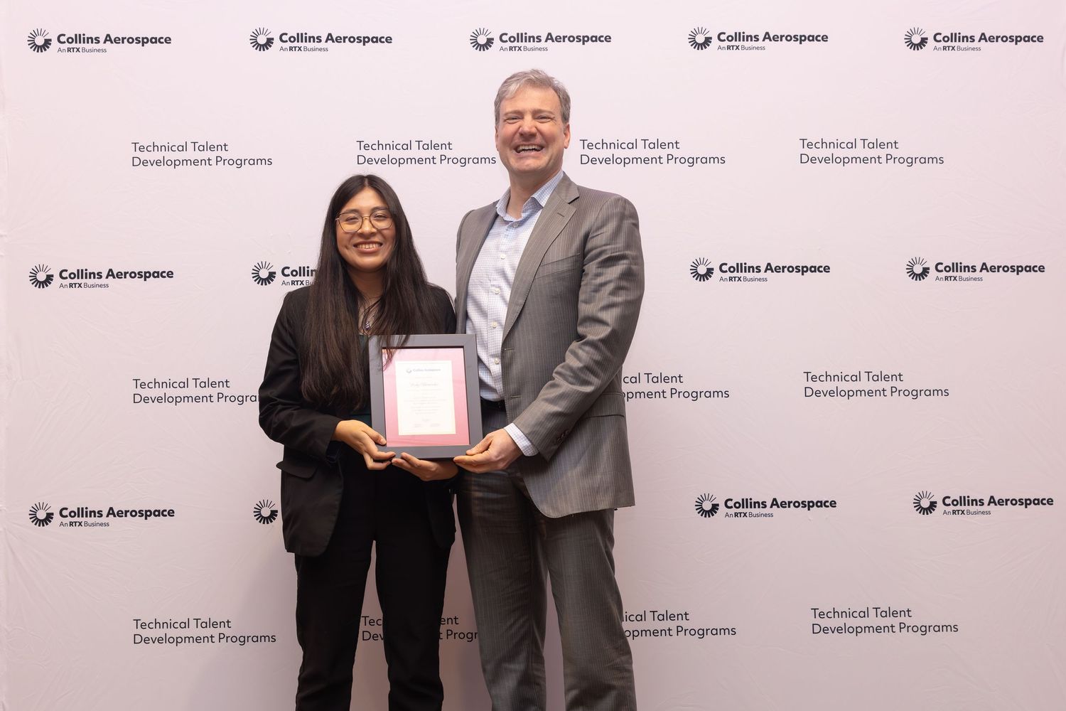 Two professionals pose with an award certificate at a Collins Aerospace Technical Talent Development Programs event.