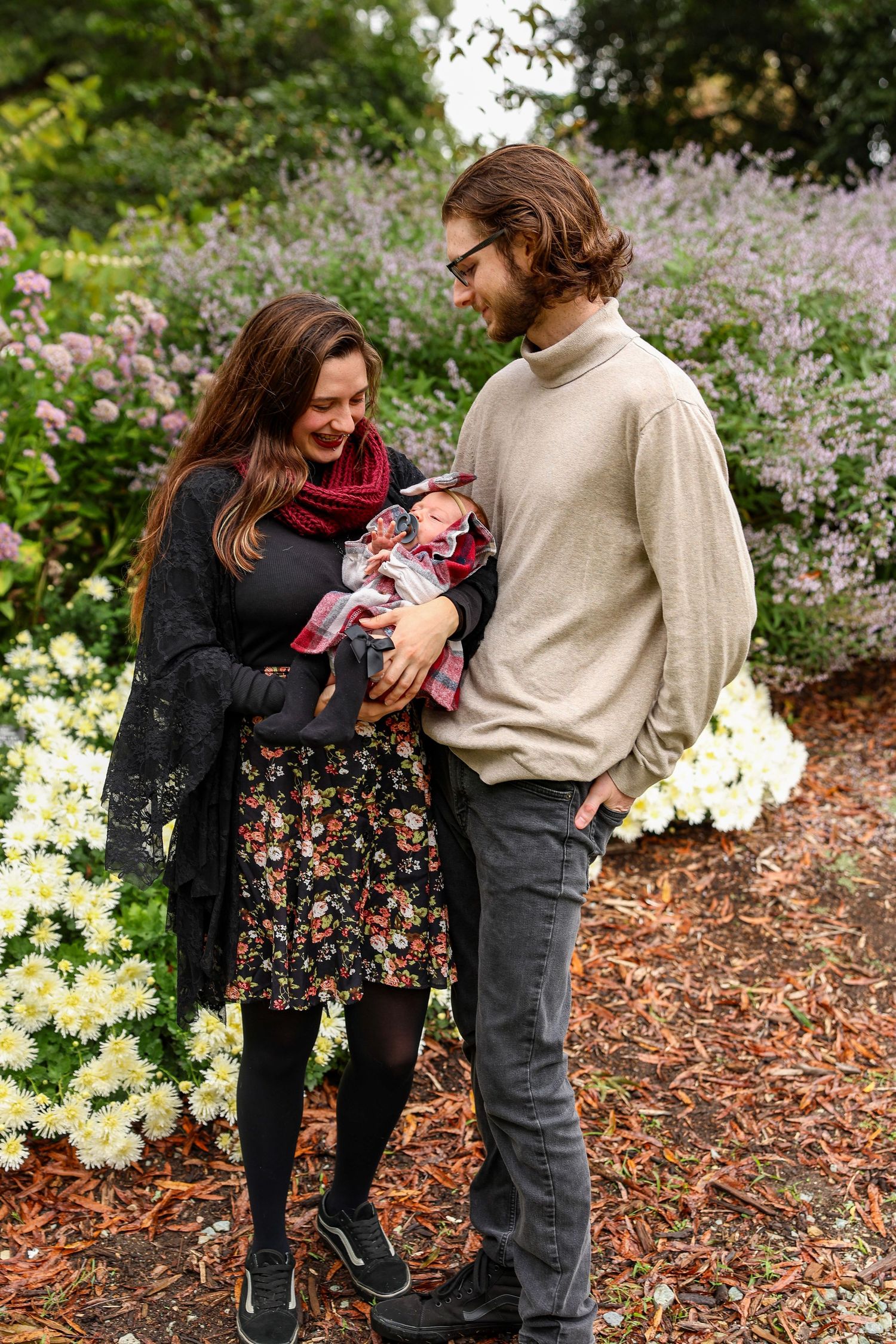 Candid moments captured between people in autumn clothing against flowering garden backdrop.