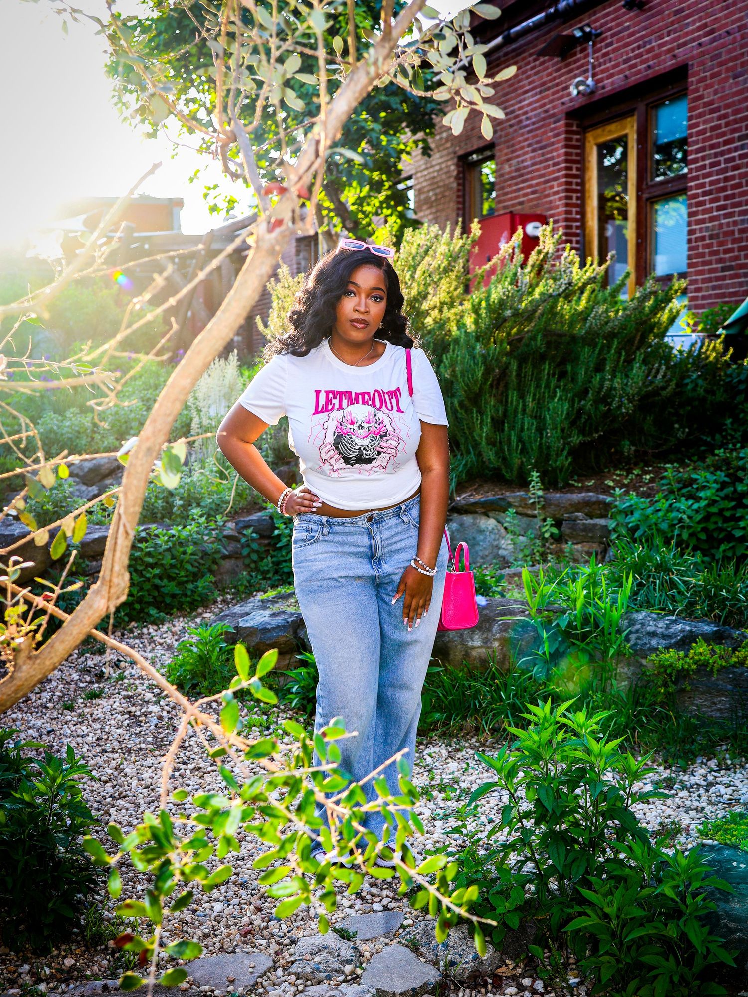 Garden photoshoot featuring lush greenery and brick building backdrop in natural lighting.