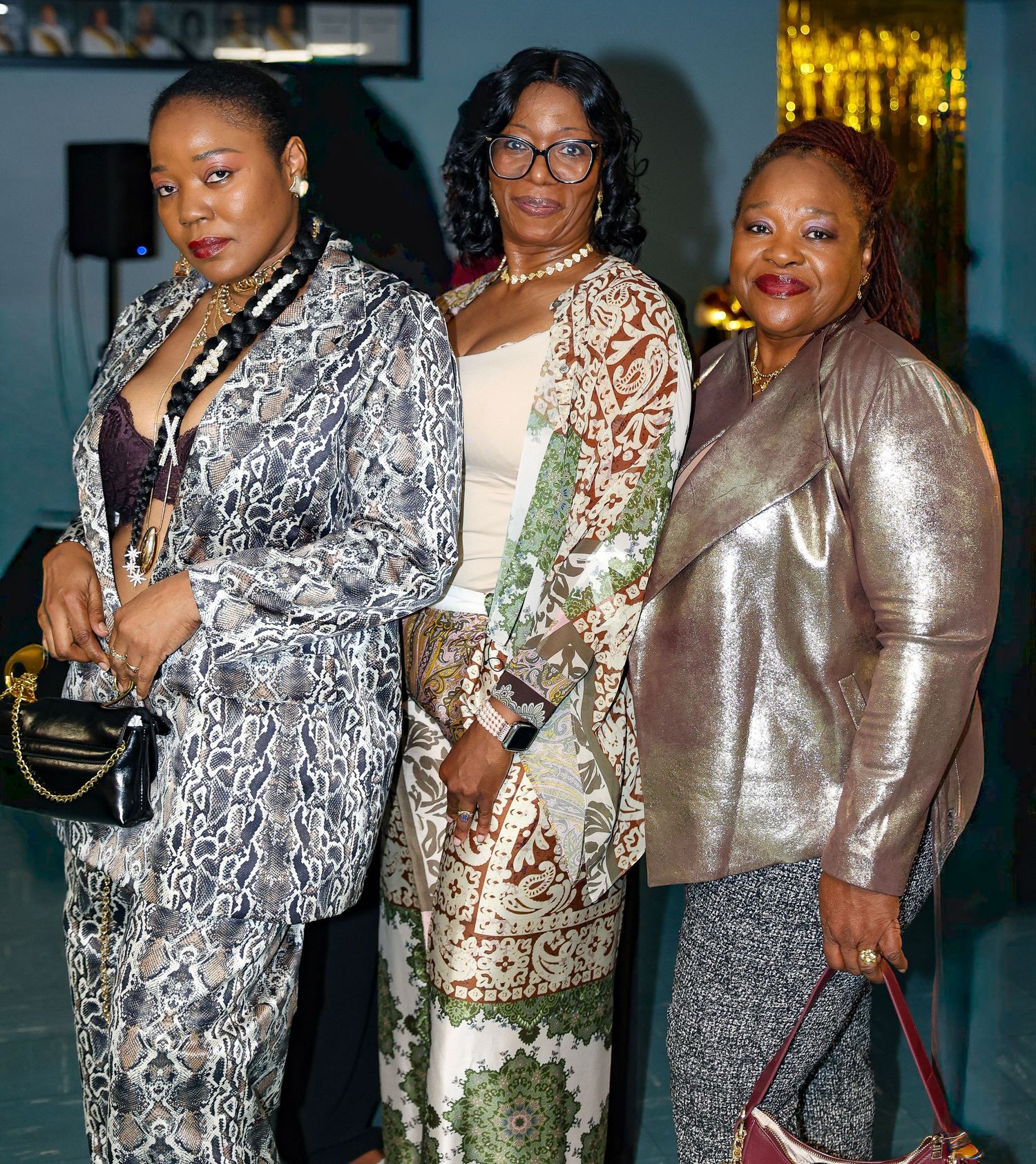 Guests wearing sparkly metallic and floral dresses pose together at a formal evening event.