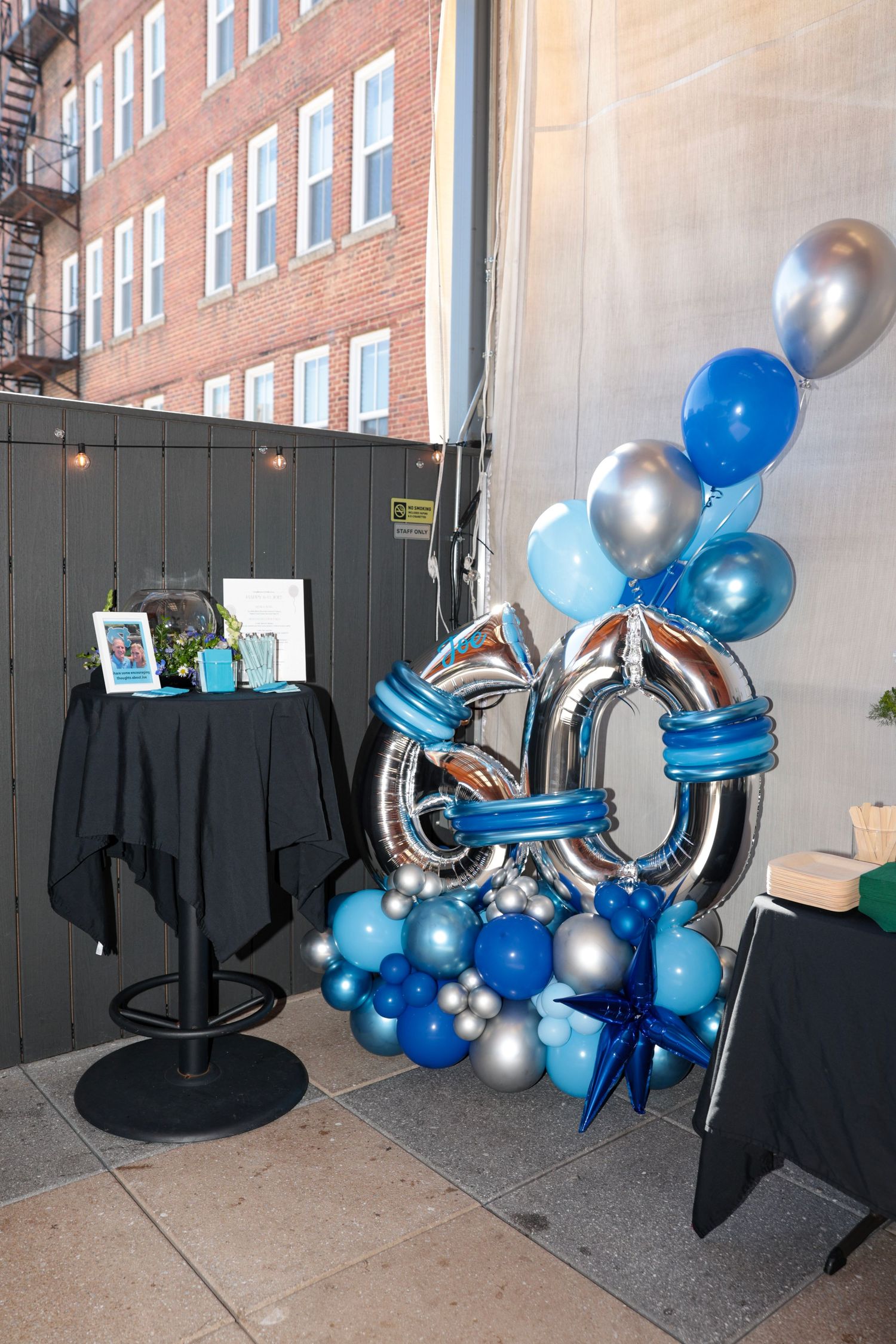 Blue and silver balloon arch display with a '60' number arrangement at an indoor party venue.