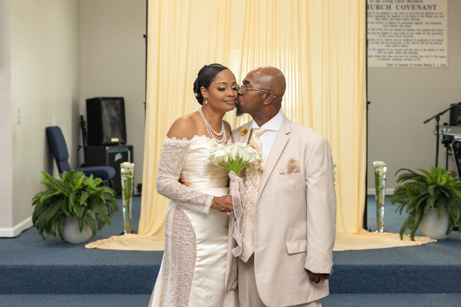 Bride and groom share a kiss at the altar during their wedding ceremony in a church.