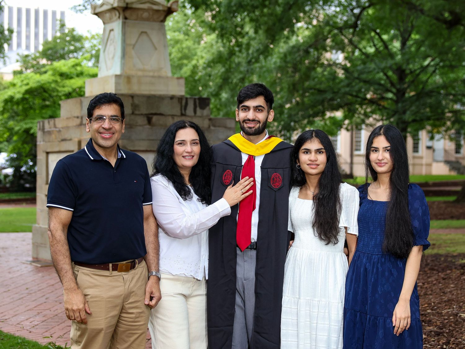 A graduation celebration photo with family members on a brick pathway near a stone monument.