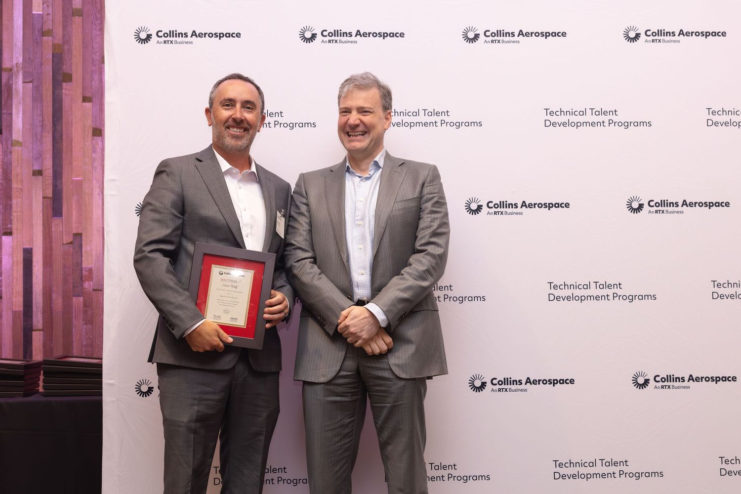 Two men pose with a framed certificate at a Collins Aerospace Technical Talent Development Programs ceremony.