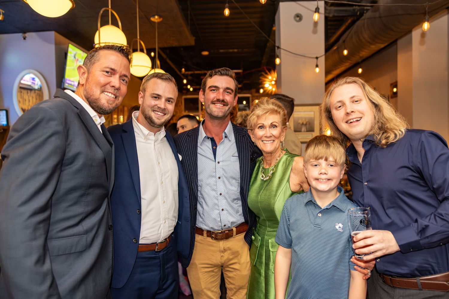 Group of six people smiling together at a casual indoor social gathering or networking event.