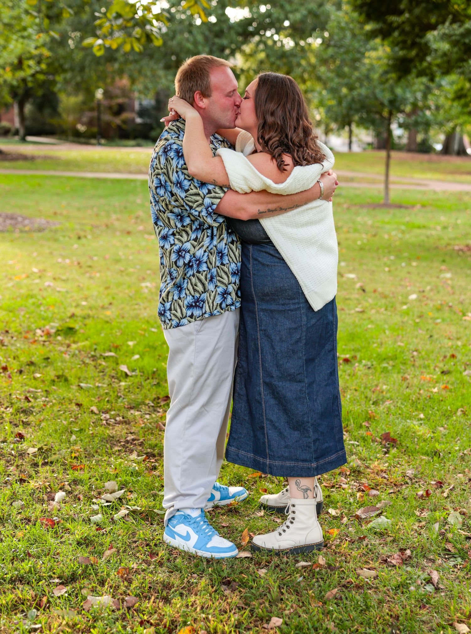 Candid outdoor engagement photos taken on grassy campus grounds.