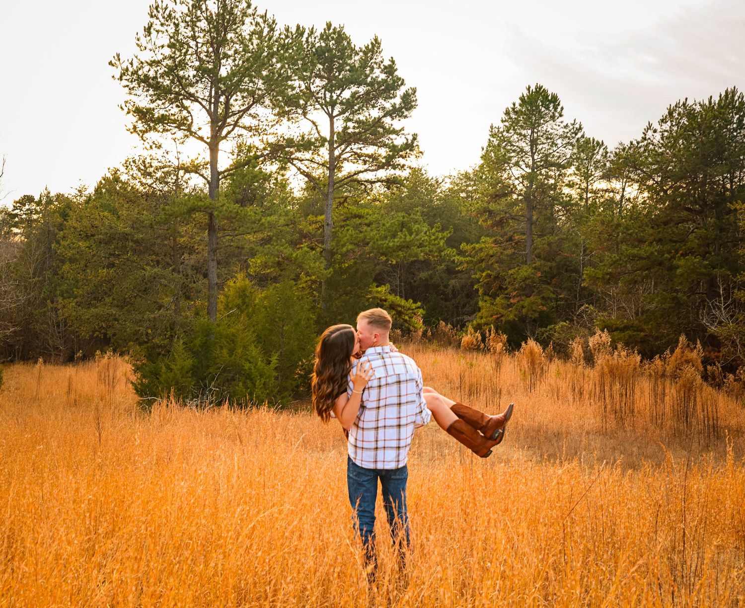 Romantic couple walking through golden field at sunset.
