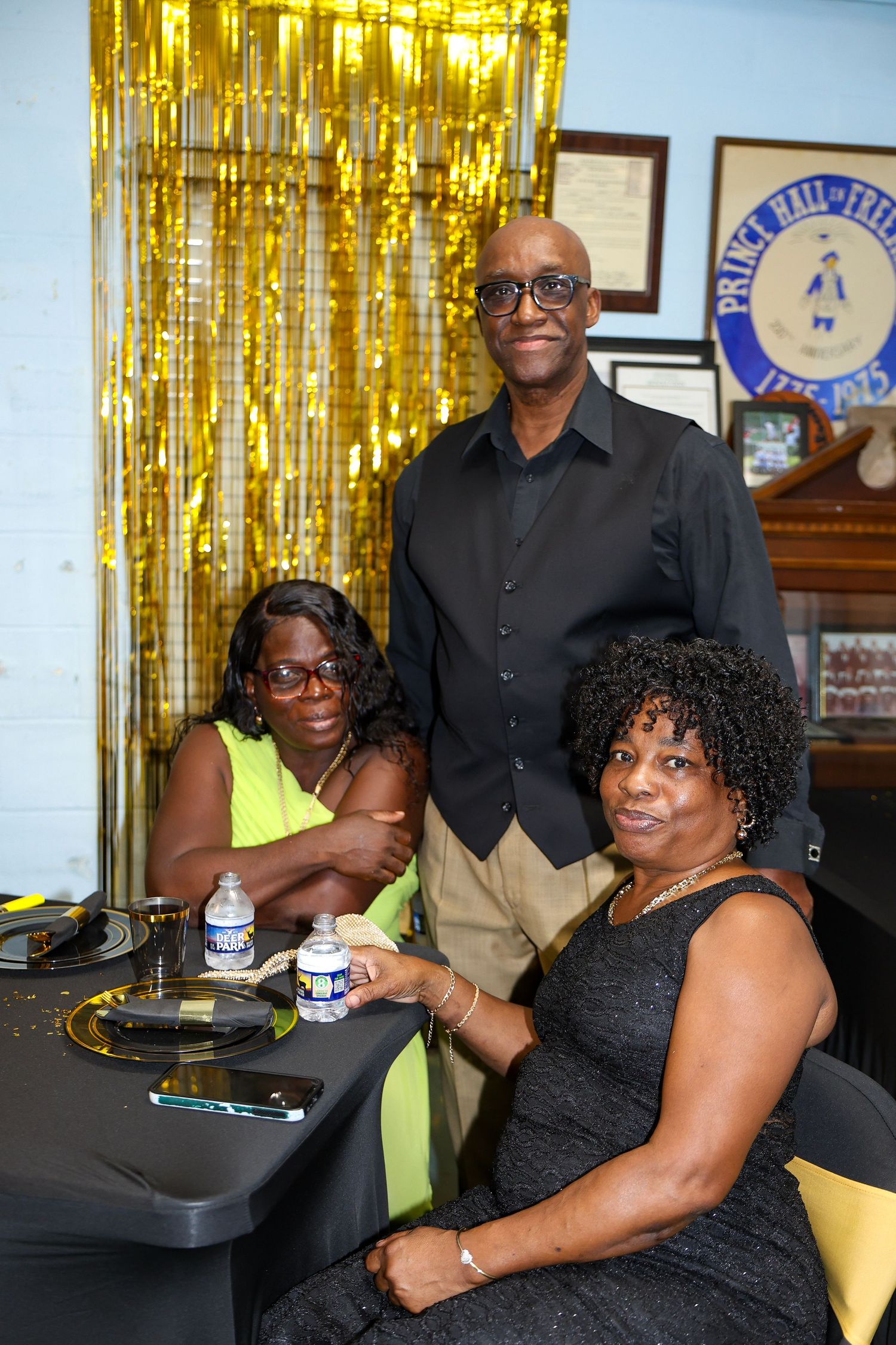 Party guests gathered near gold tinsel decorations at a celebration.