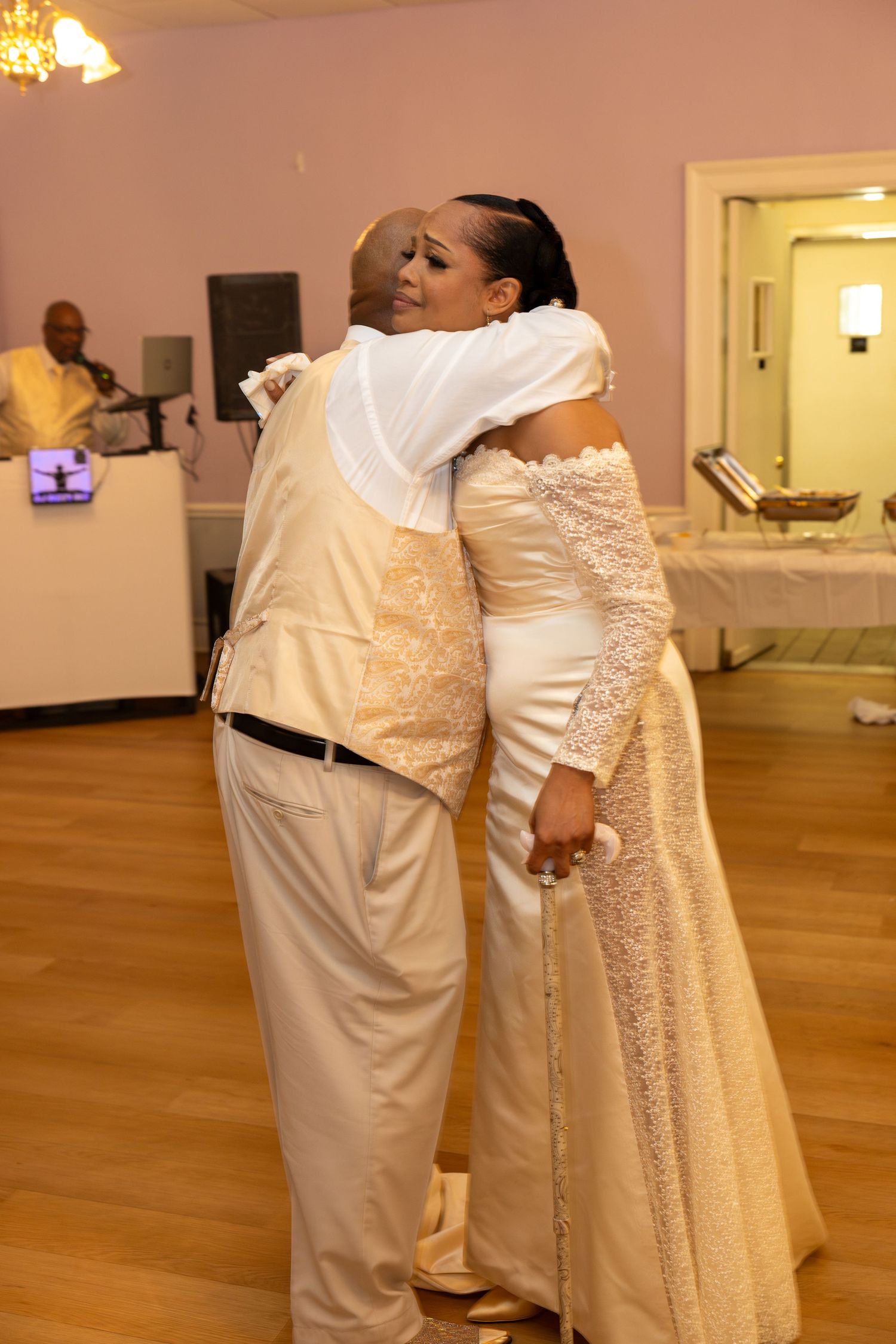 Bride and groom share a warm embrace during their first dance at an elegant wedding reception.