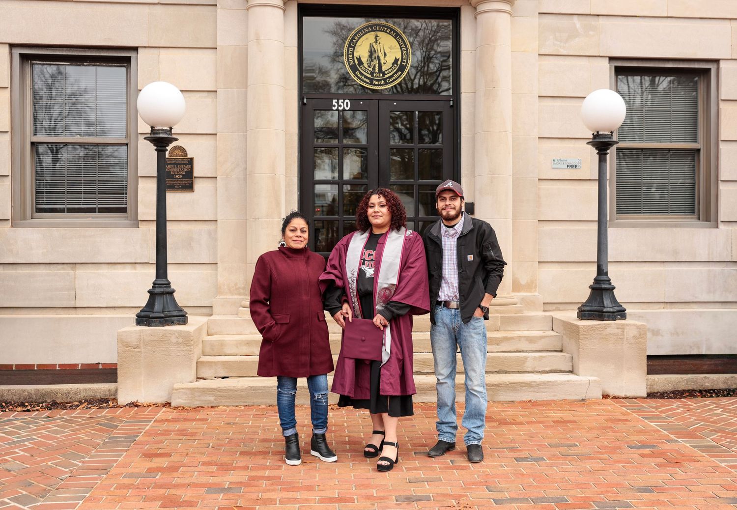 A wide view of people standing in front of a classic stone building entrance.