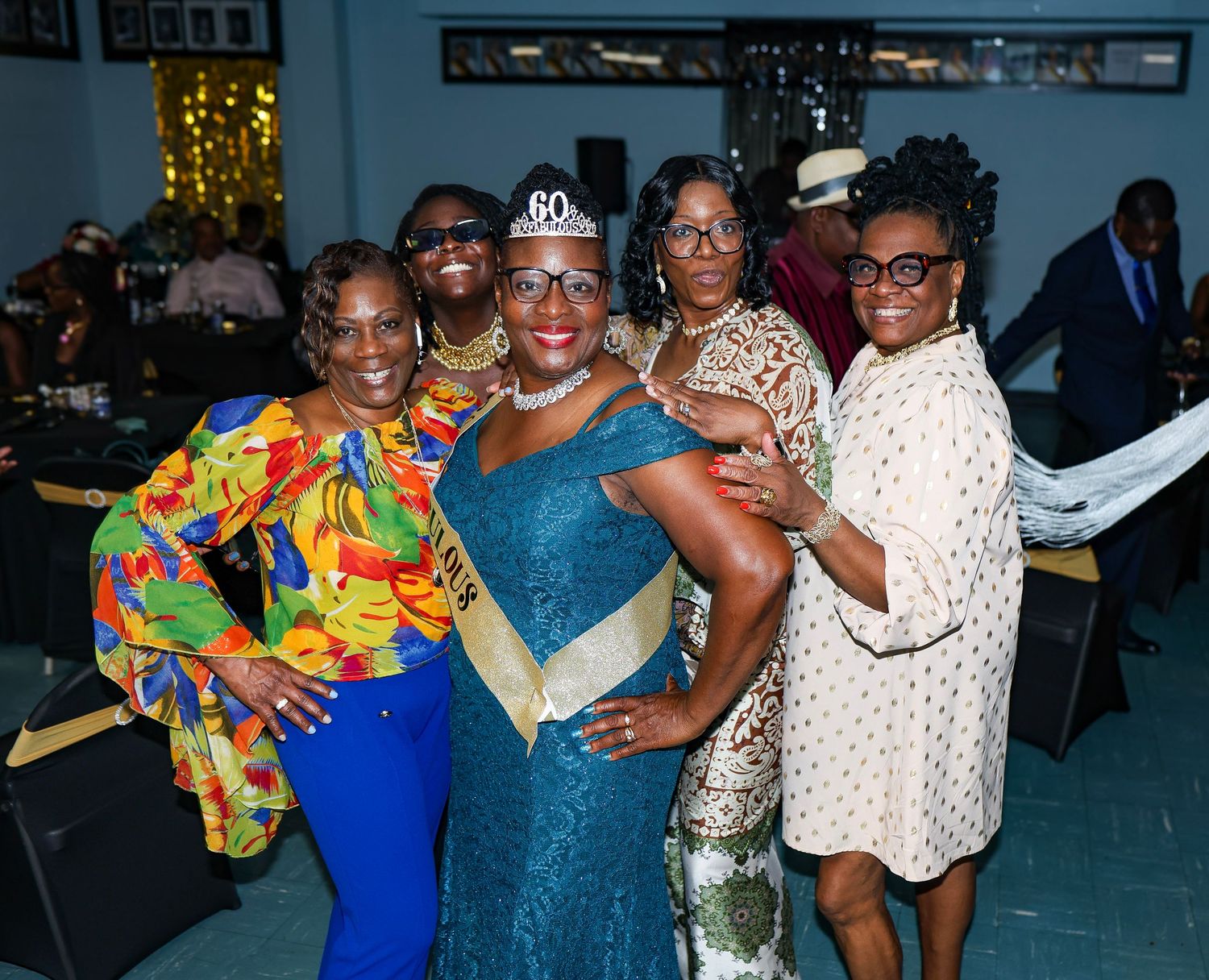 A group poses together at a celebration with one wearing a blue dress and tiara in the center.