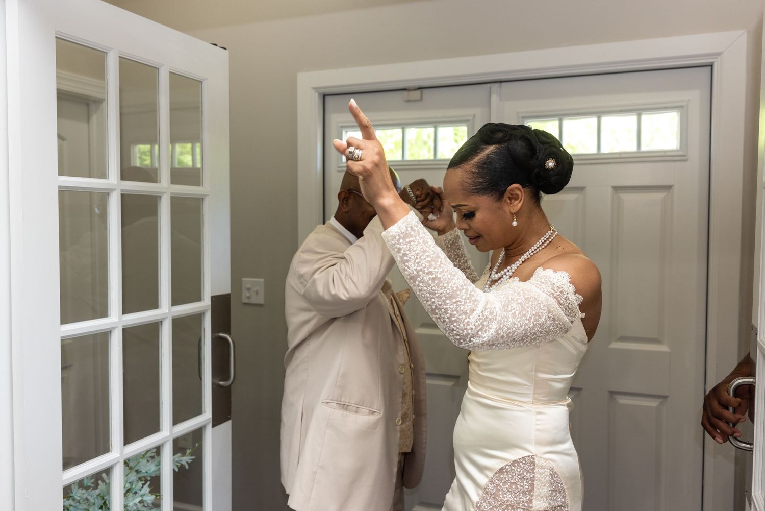 Bride and groom sharing a joyful first look moment, with bride in white lace gown and groom in tan suit.
