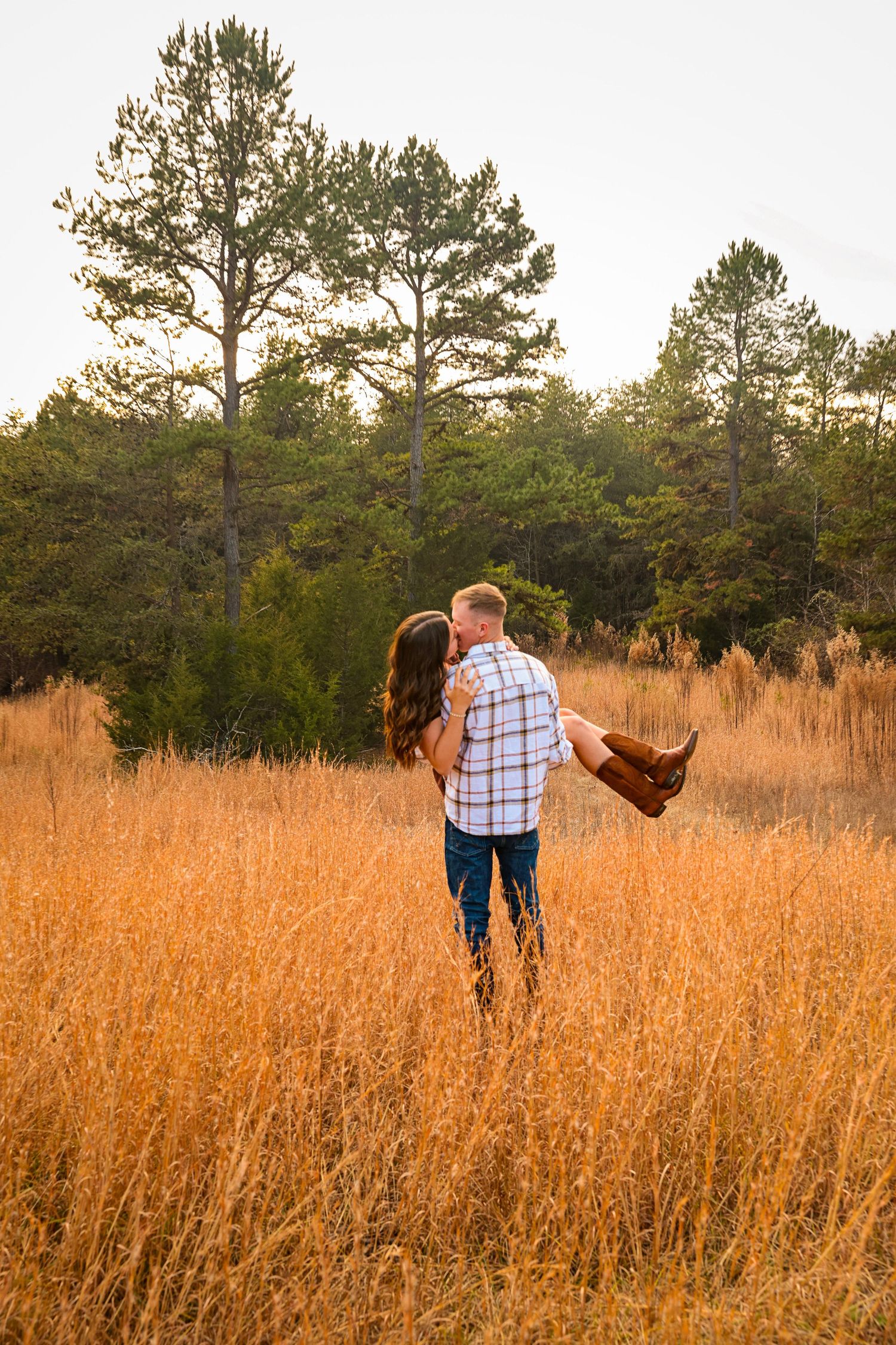 Two people walk hand in hand through a scenic autumn field at dusk.