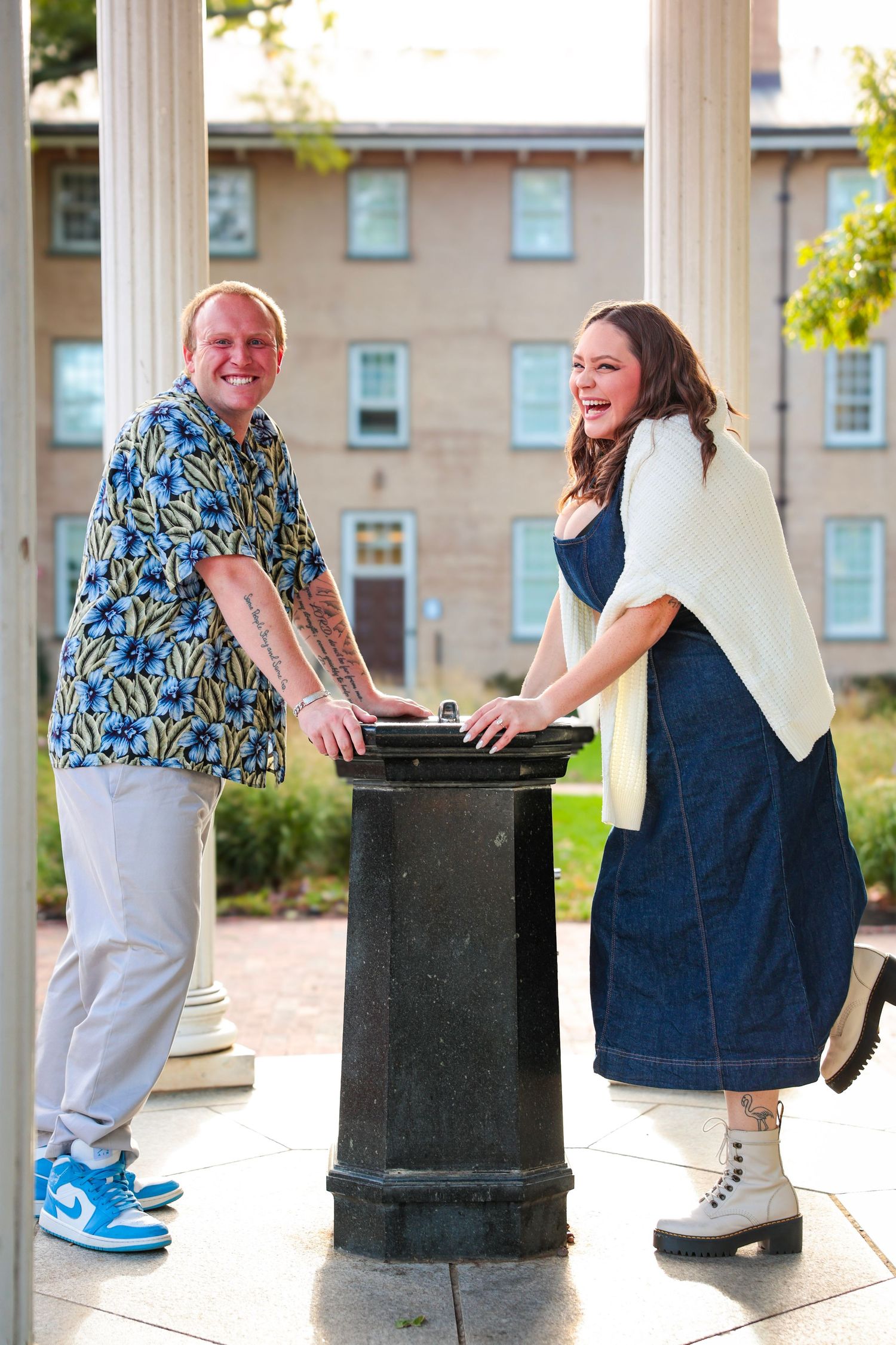 Playful couple poses by columns and decorative posts in an outdoor gazebo setting.