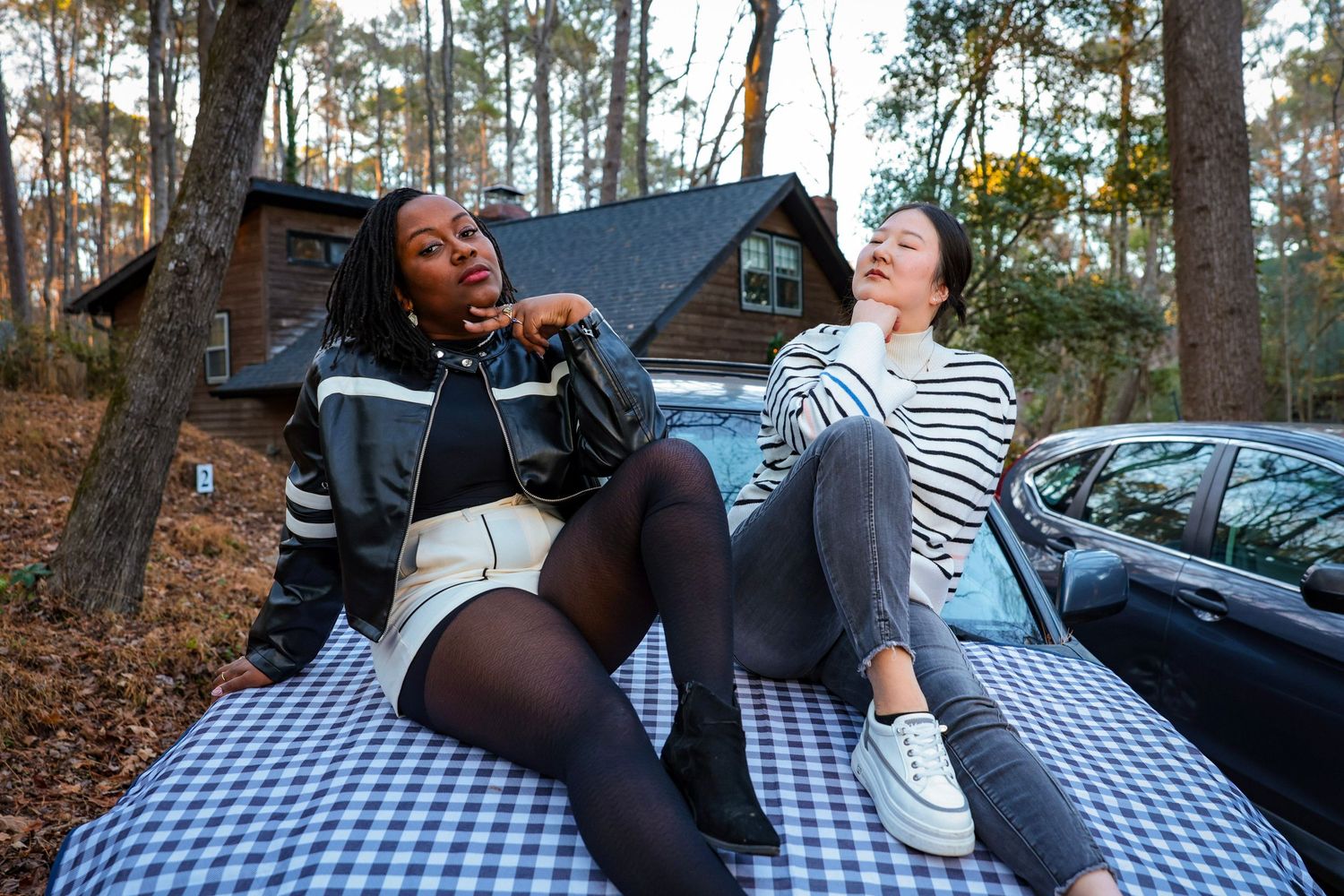 Candid moments of friends laughing while lounging on checkered blanket in forest.