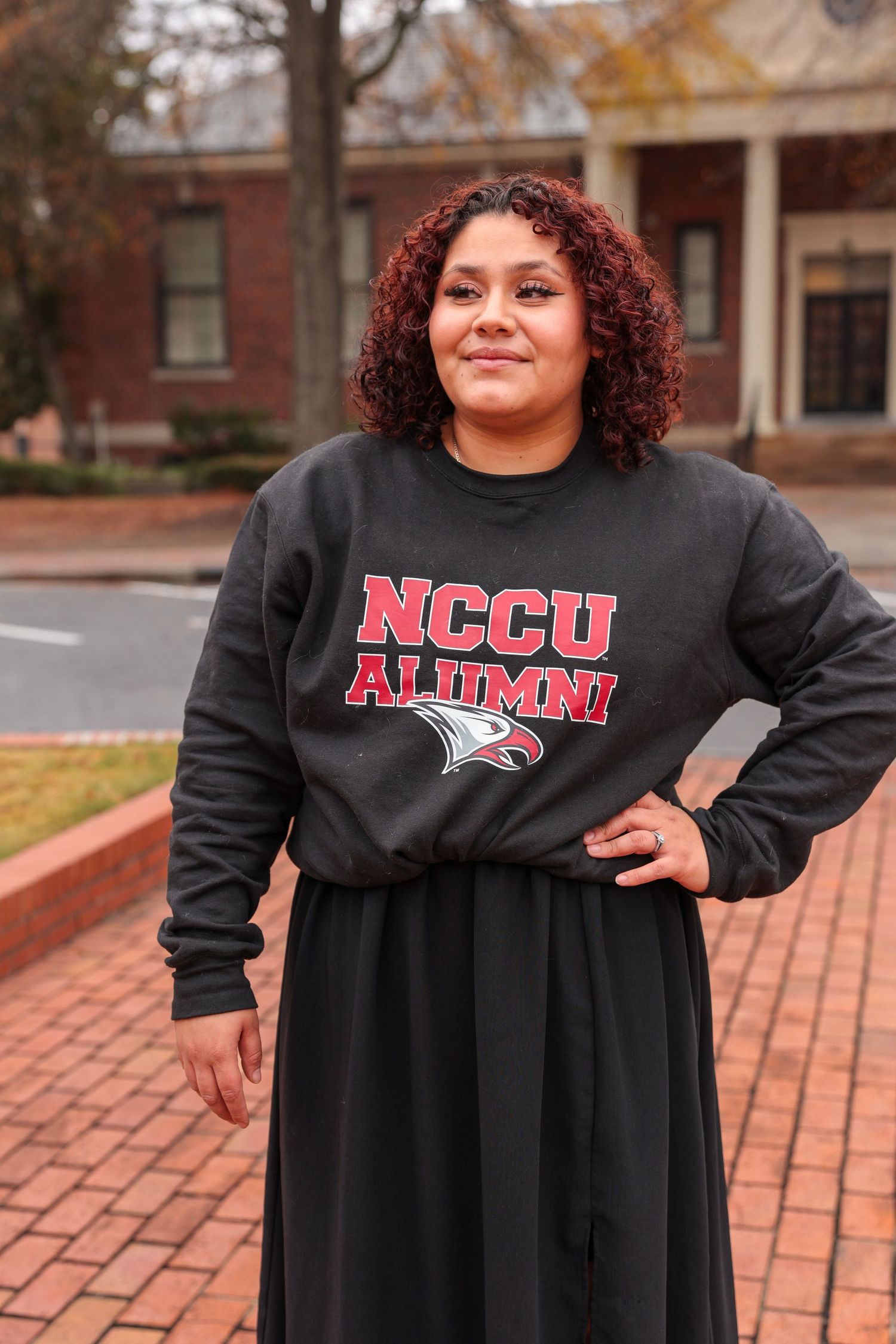 NCCU Alumni sweatshirt and graduation attire photographed outdoors.