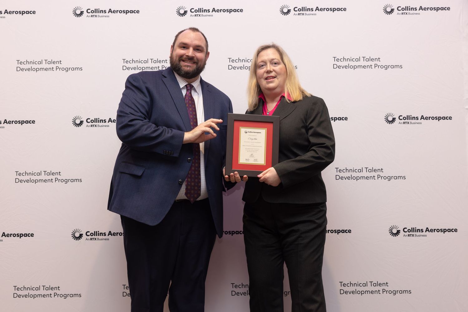 Man and woman holding a framed award at Collins Aerospace Technical Talent Development Programs ceremony.
