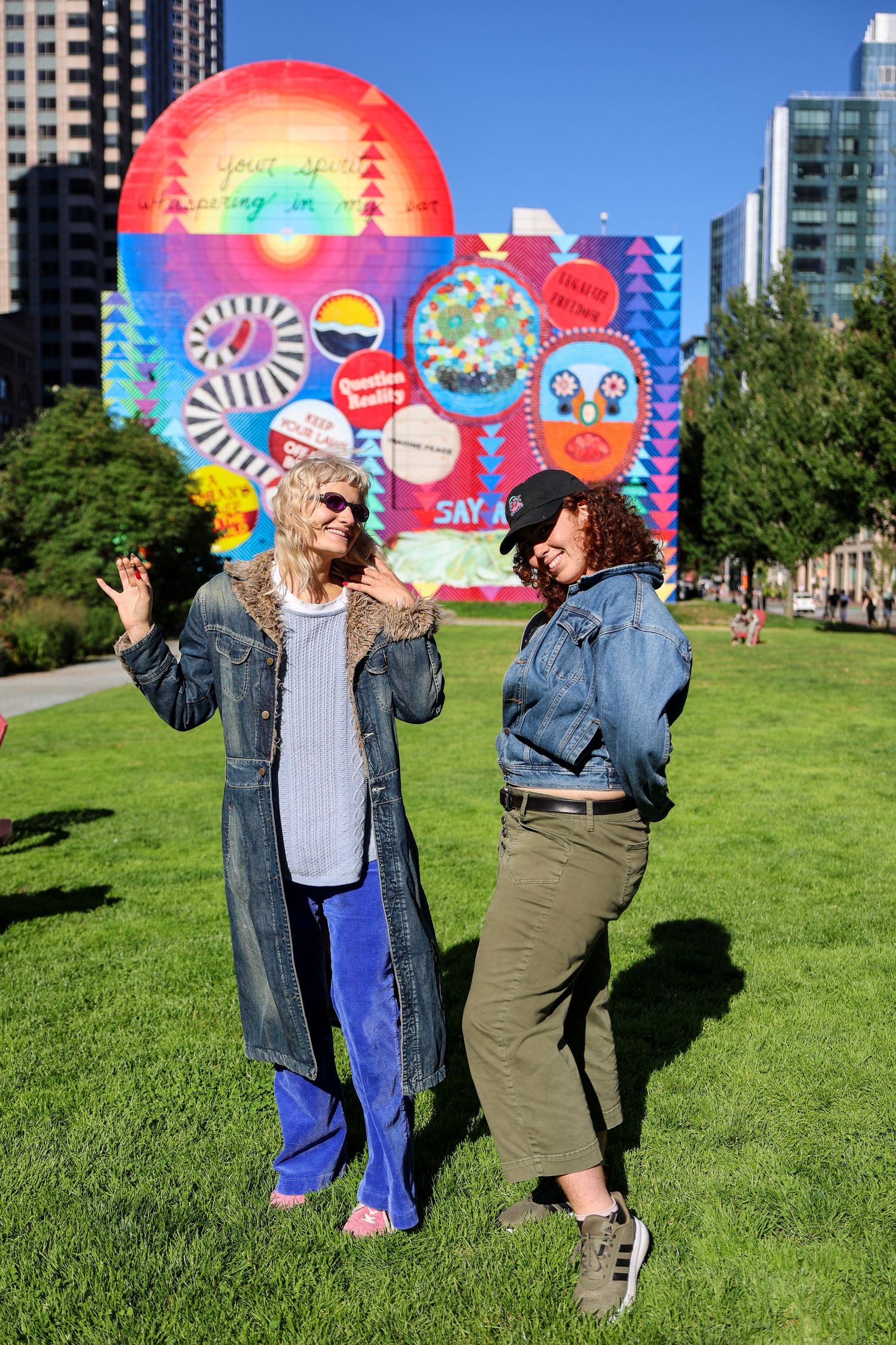 Friends in denim jackets dancing and having fun against a vibrant street art backdrop.