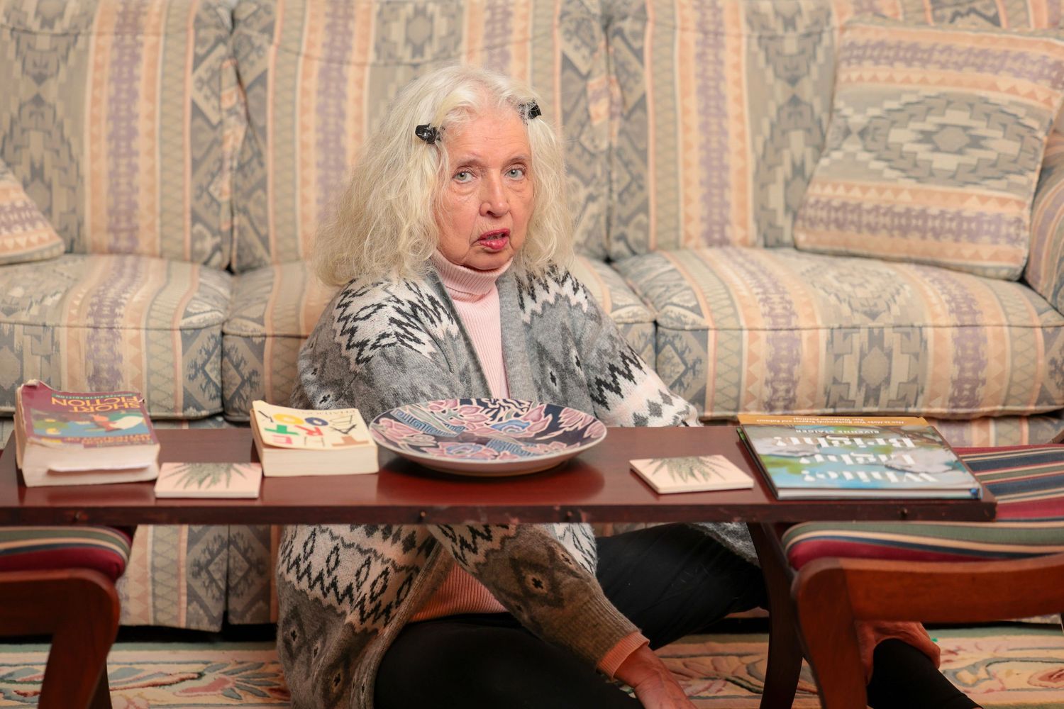 Person lounging on striped couch with coffee table and books in view.