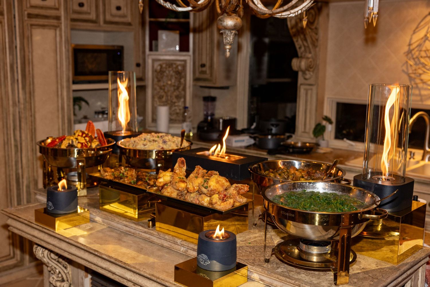 Elegant buffet table with chafing dishes, bread baskets and candles displaying a variety of catered foods.