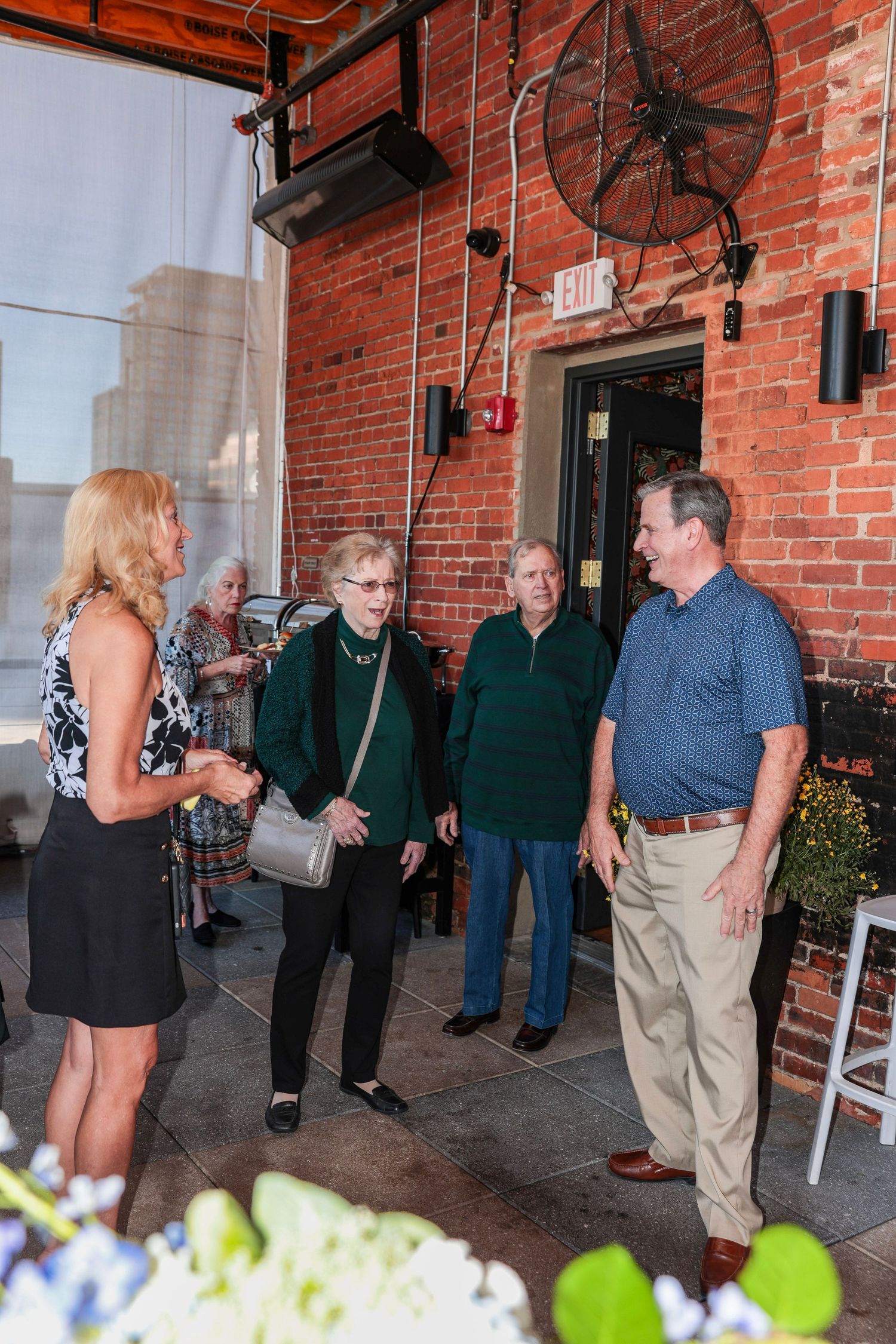 Social gathering in a rustic brick venue with industrial lighting and floral decorations.