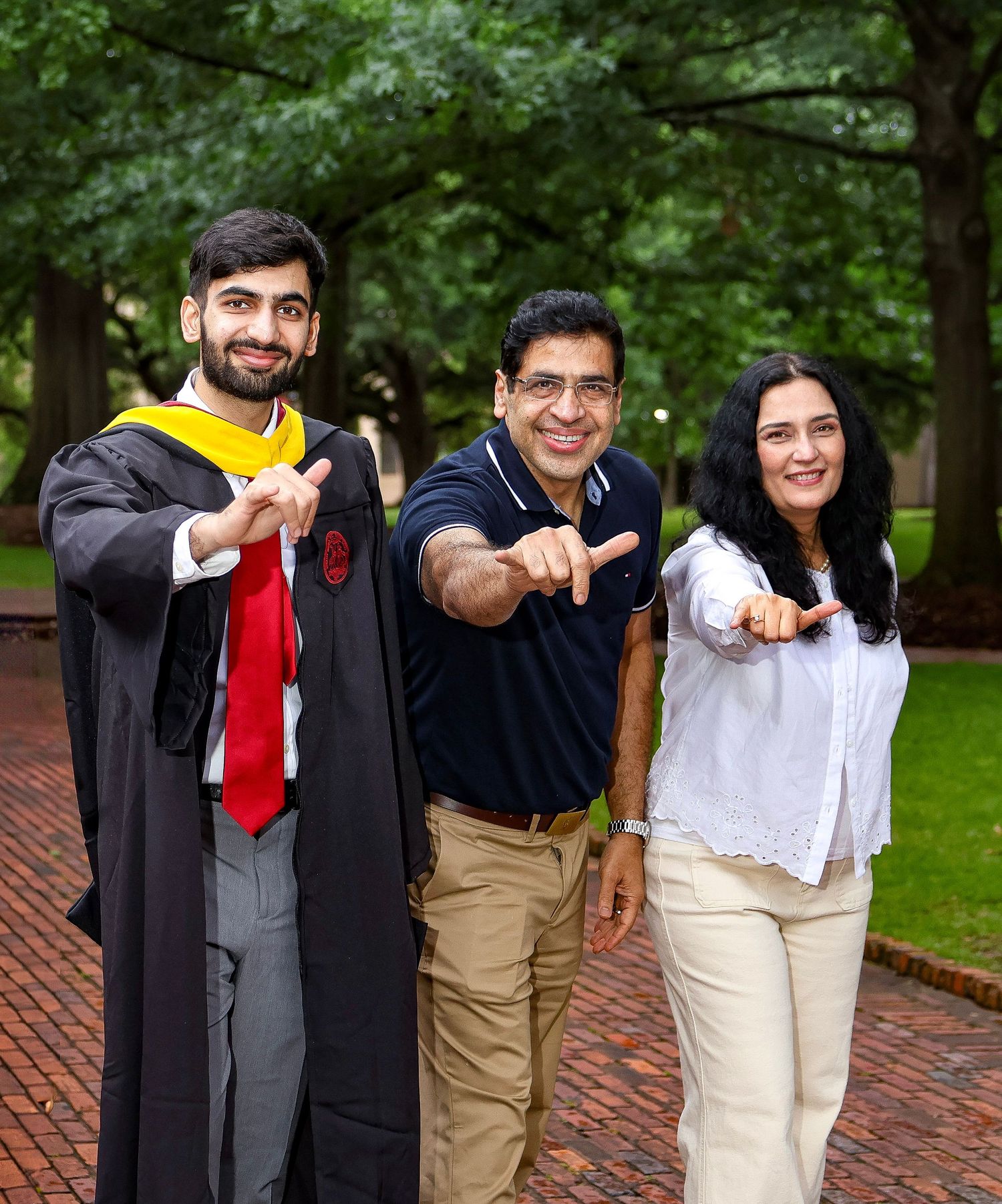 Family poses together pointing forward on brick pathway during graduation.