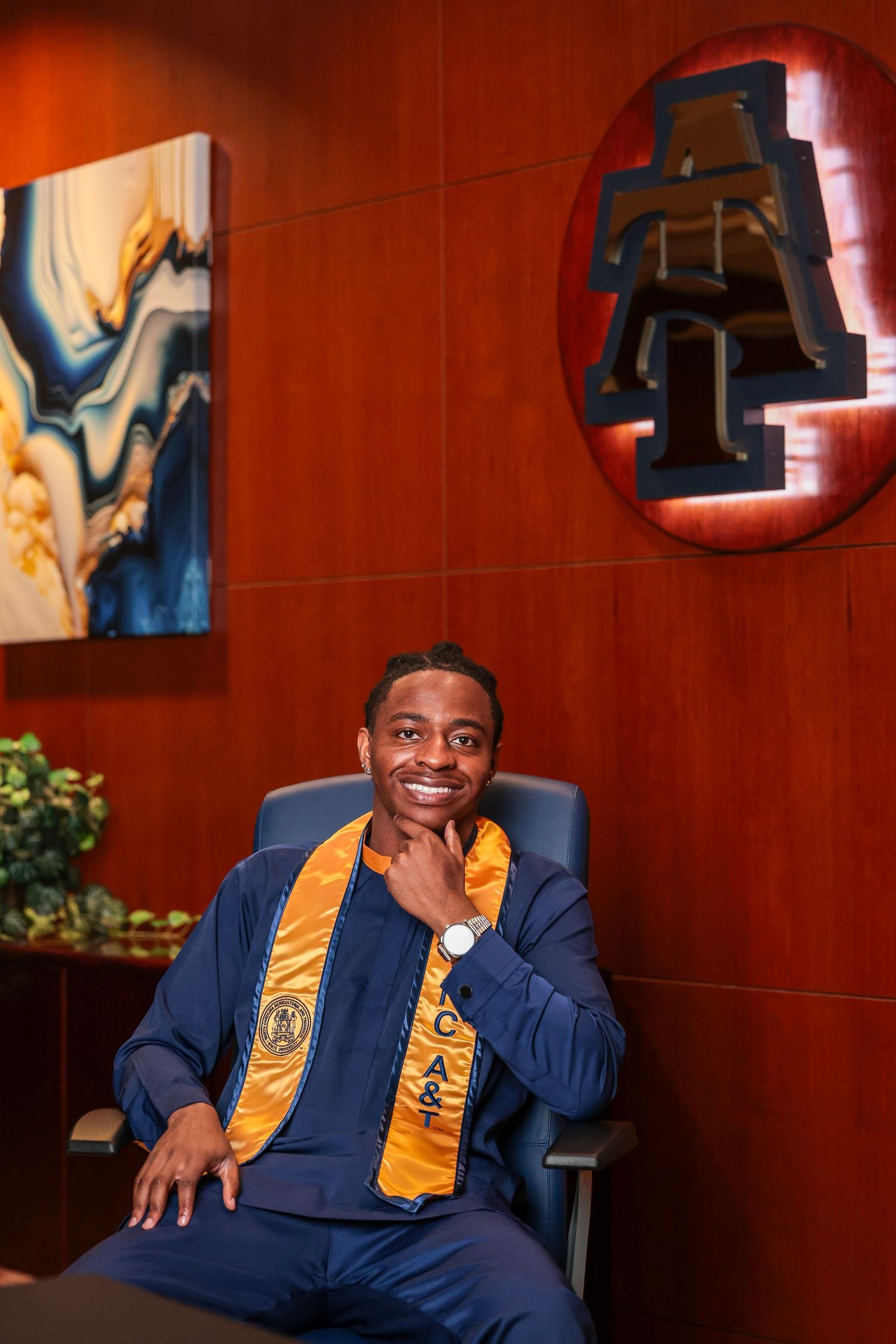 Graduate in academic regalia smiles during indoor graduation photoshoot.