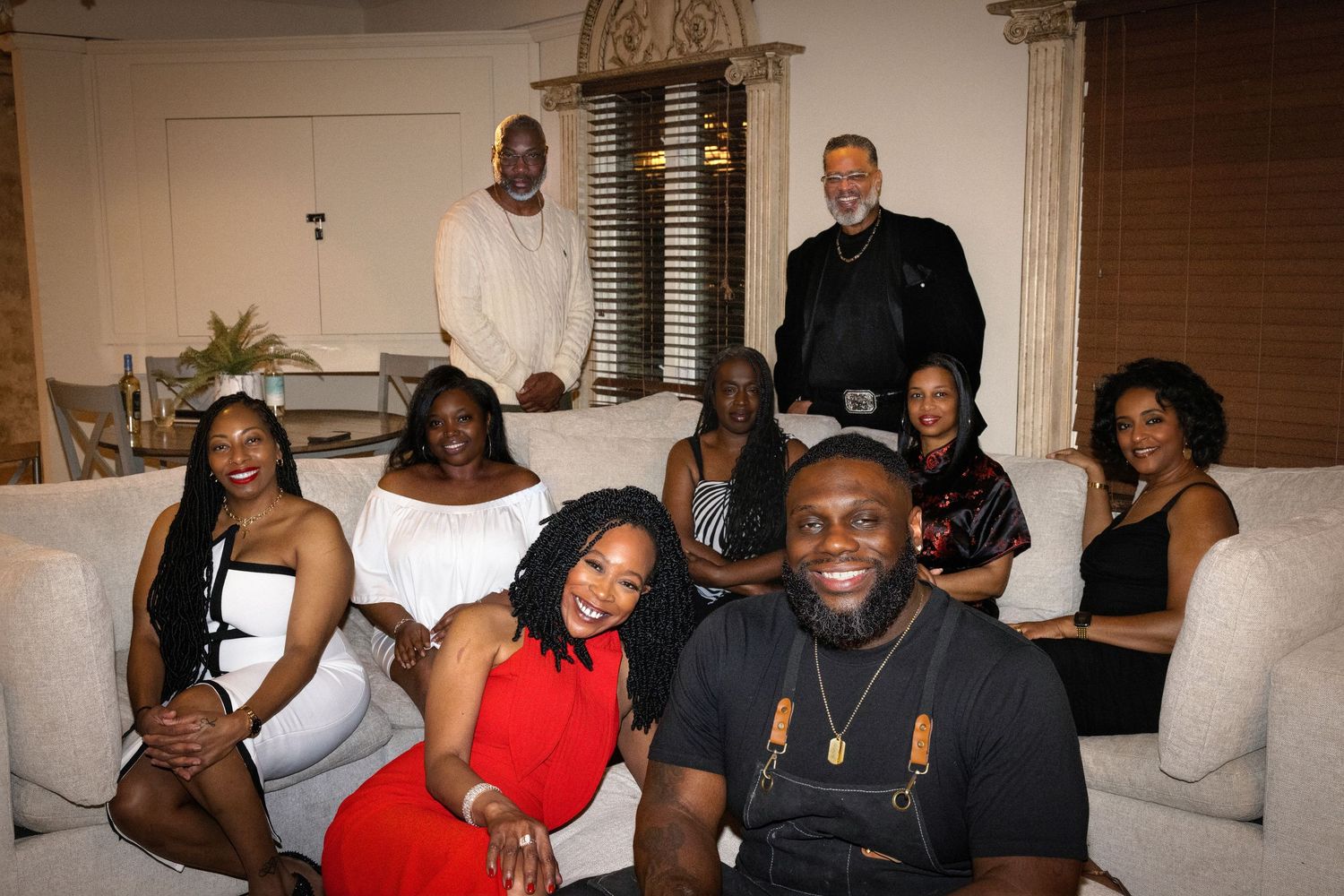 A group of people enjoying a social gathering in an elegant room with chandelier lighting.
