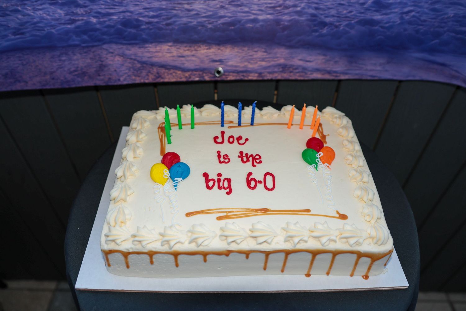 A white birthday cake decorated with colorful candles and 'big 60' written in red frosting.