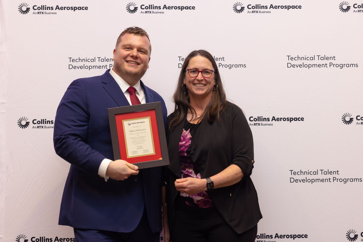 Two professionals pose with a framed award at Collins Aerospace Technical Talent Development Programs event.
