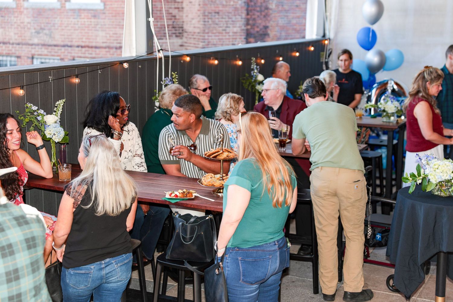 Celebration in a modern industrial venue with blue balloons and black decor accents.