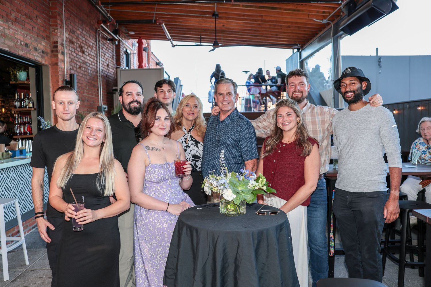 Group of people gathered at rooftop bar celebration with drinks and appetizers.