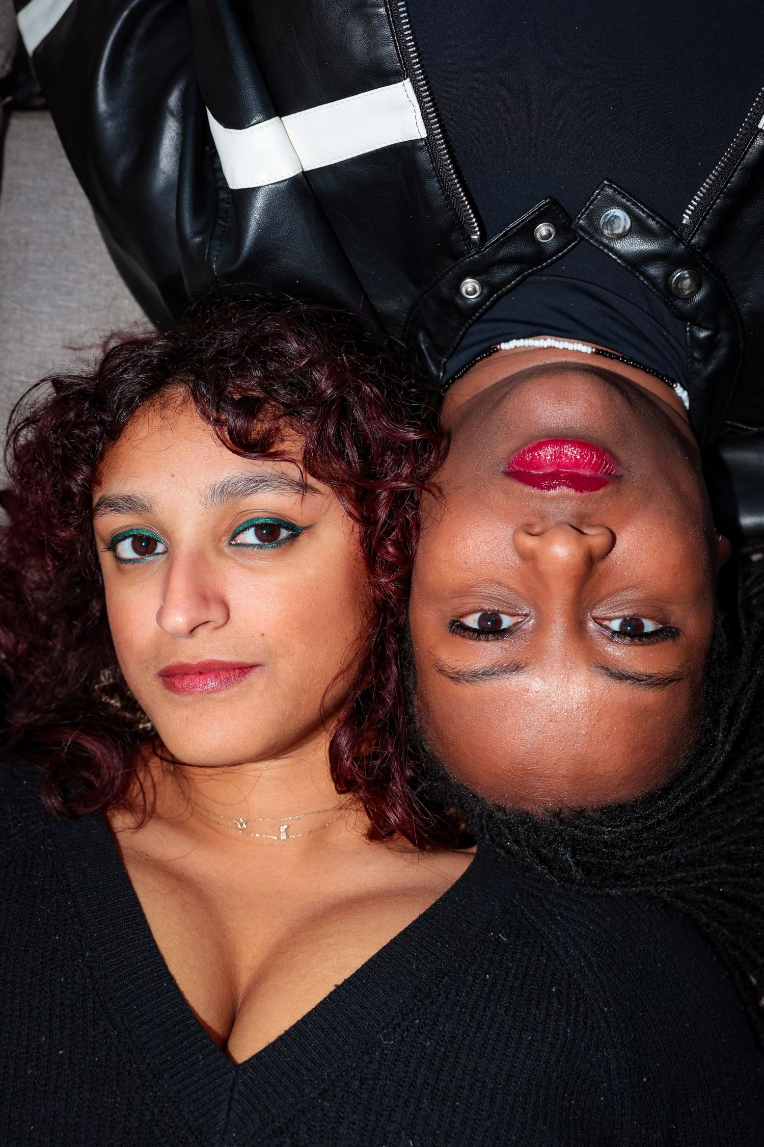 Creative portrait of two people with vibrant makeup lying head to head in contrasting positions.
