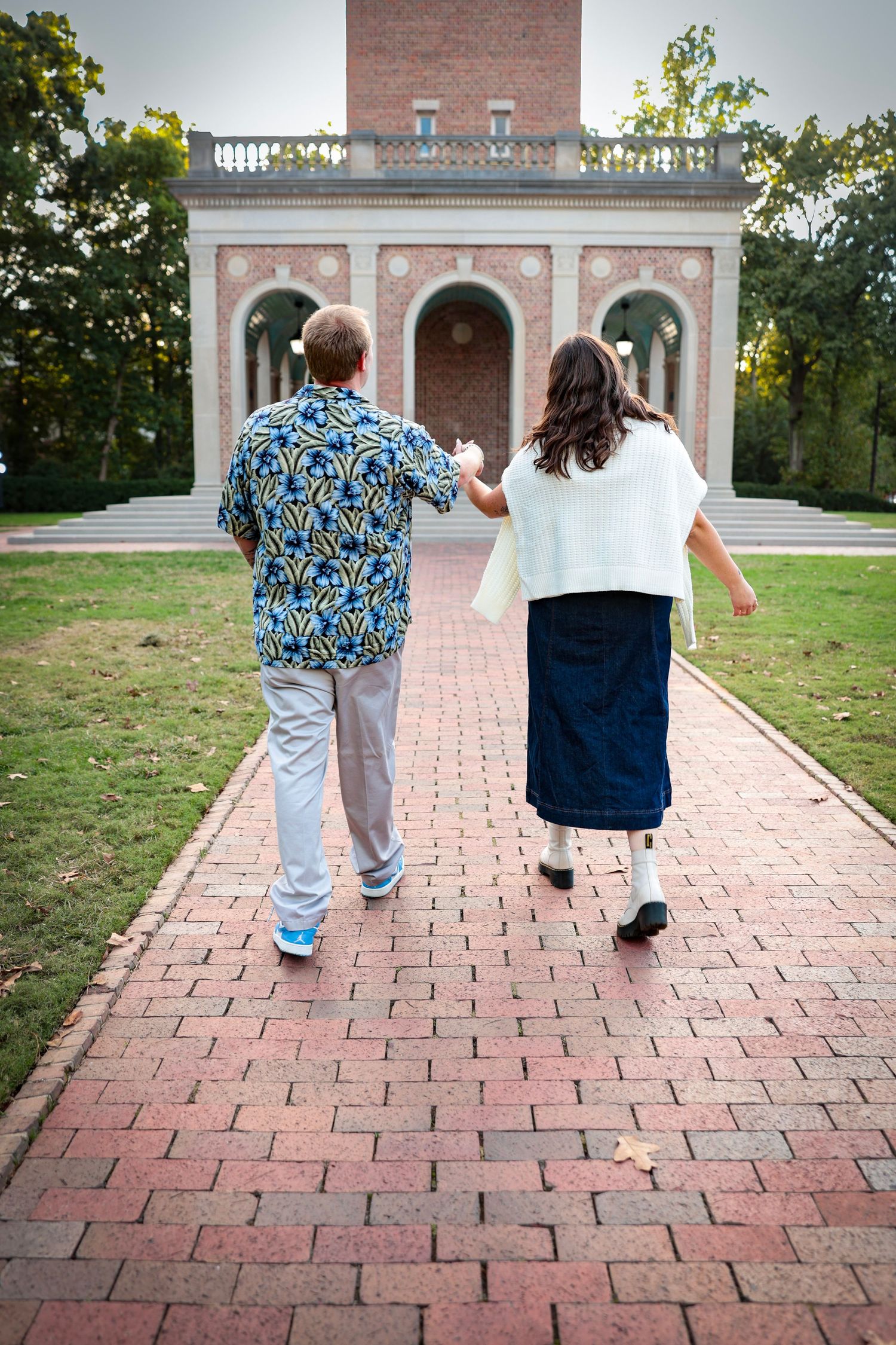 Walking away shot of a couple on a brick pathway leading to a historic building.