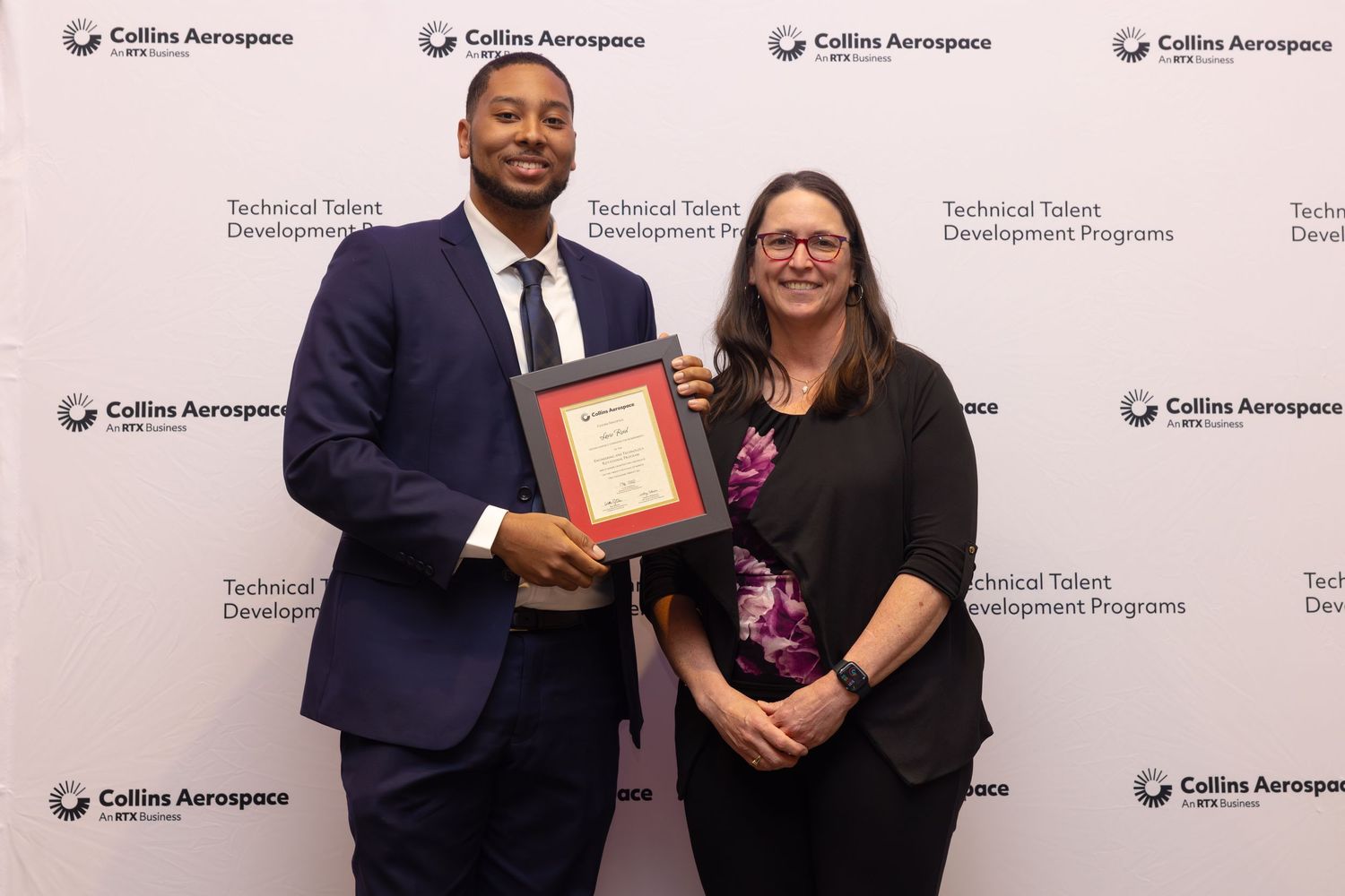 Man and woman smile holding a framed award at Collins Aerospace Technical Talent Development Programs event.